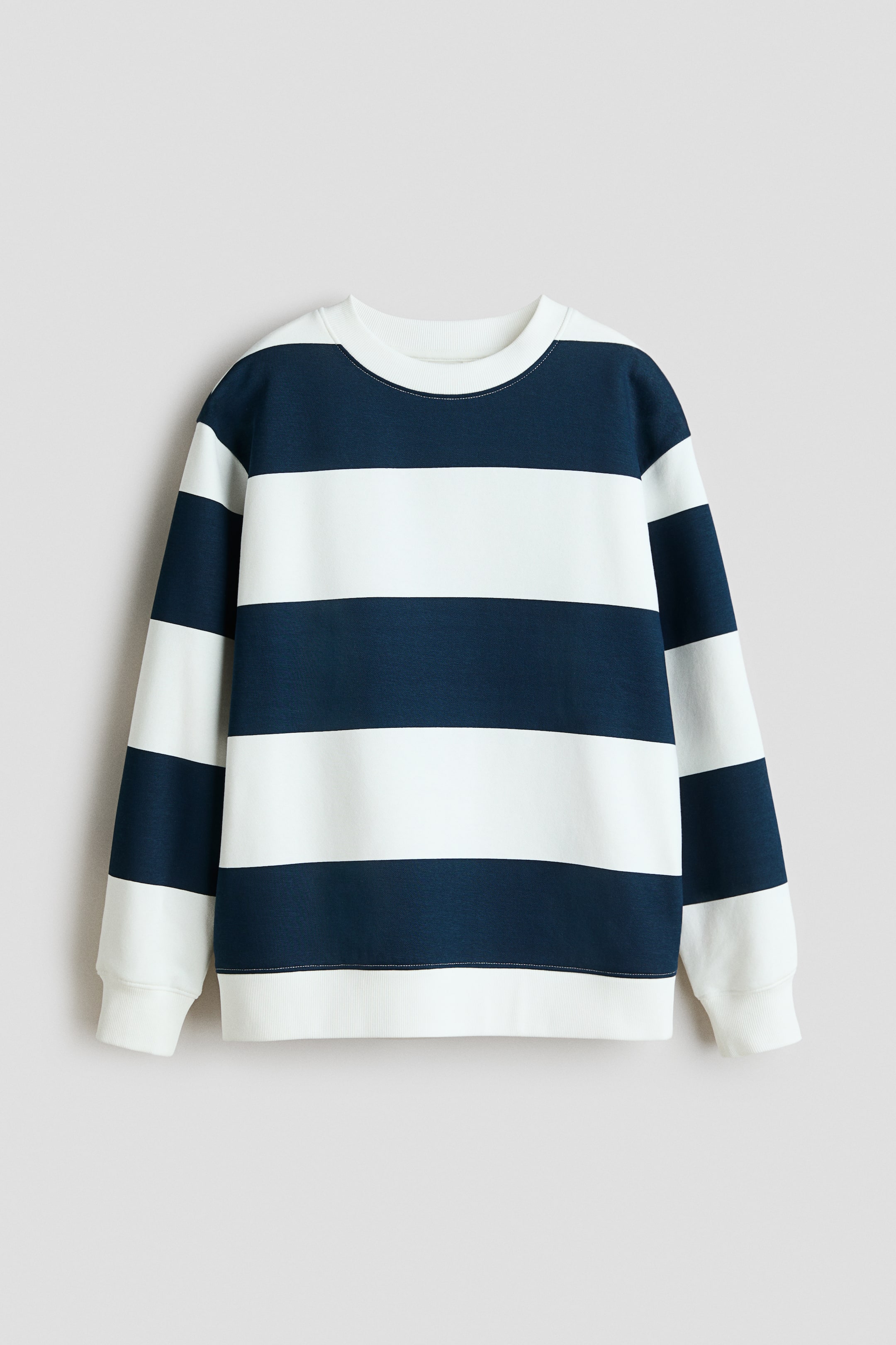Größeres Bild anzeigen: Ein langärmliges Oberteil aus Sweatshirtstoff zeigt marineblaue und weiße horizontale Streifen auf der Vorderseite. Es verfügt über einen gerippten Rundhalsausschnitt, gerippte Bündchen und einen gerippten Saum.