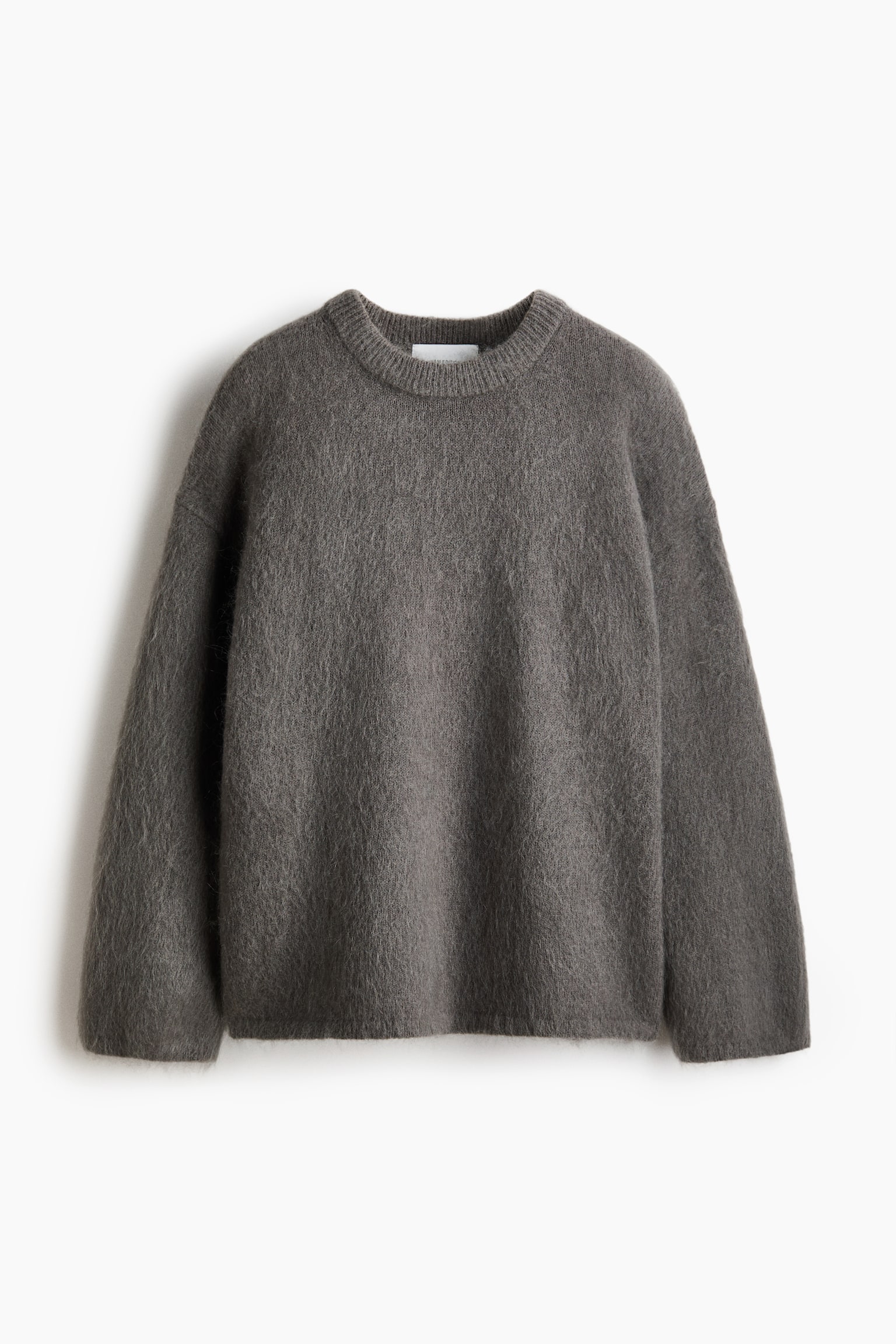 A dark grey oversized jumper featuring a soft, brushed knit with a hairy texture. It presents flat with dropped shoulders, long sleeves, and ribbing at the crew neckline, cuffs, and hem. - 1