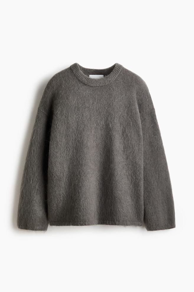 A dark grey oversized jumper featuring a soft, brushed knit with a hairy texture. It presents flat with dropped shoulders, long sleeves, and ribbing at the crew neckline, cuffs, and hem. - 1