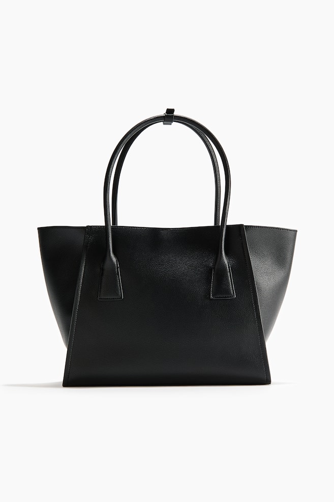 Un sac cabas noir présente son devant, mettant en avant un matériau texturé et une forme structurée et effilée avec deux poignées supérieures fines reliées par une petite sangle. - 1