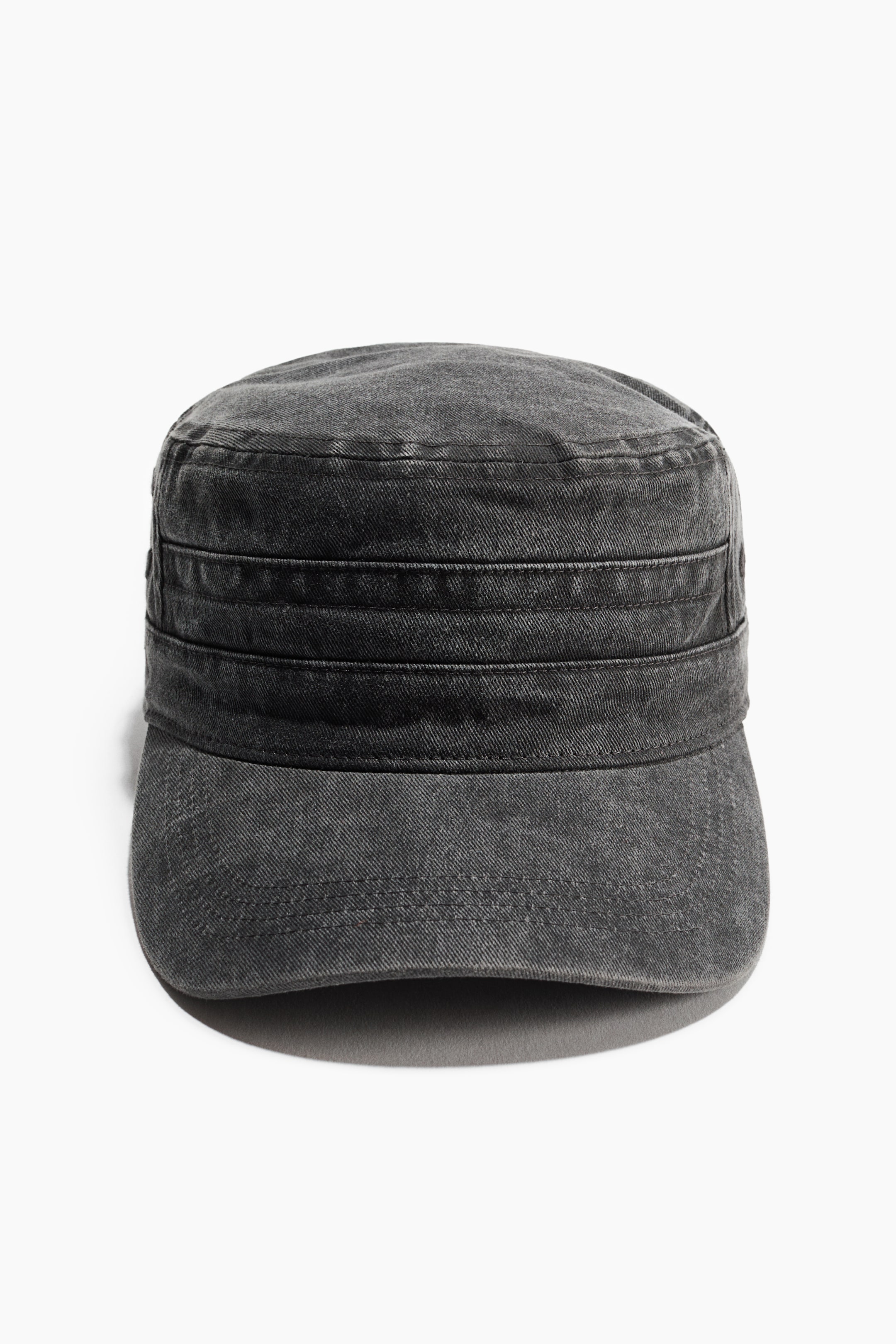 Grotere afbeelding bekijken: Een donkergrijze cadet cap van gewassen denim is van voren te zien, met een vlakke kroon en een gestructureerd cilindrisch ontwerp. De pet heeft horizontaal gestikte panelen rondom de band en een gebogen klep met zichtbare doorstiknaden.