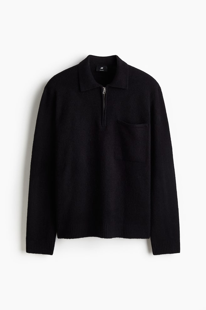 A black jumper, presented from the FRONT, is featuring a soft, fine knit, a collar, a half-zip closure, and an open chest pocket on the left side. It is designed with long sleeves and ribbed cuffs and hem. - 1