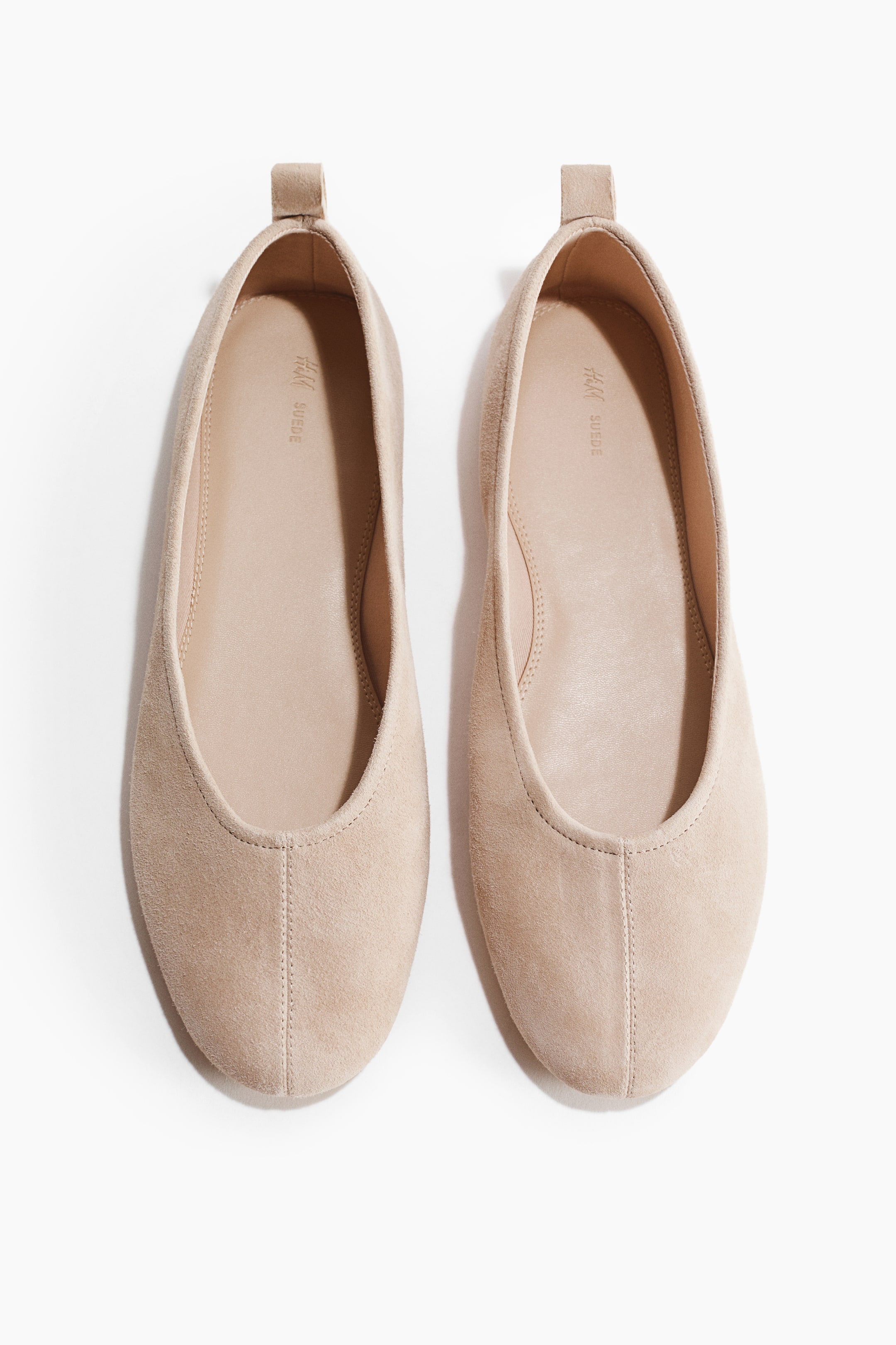 View larger image: Facing front, these ballet flats boast soft suede, rounded toes with a visible seam, and a loop at the back. They feature twill linings.