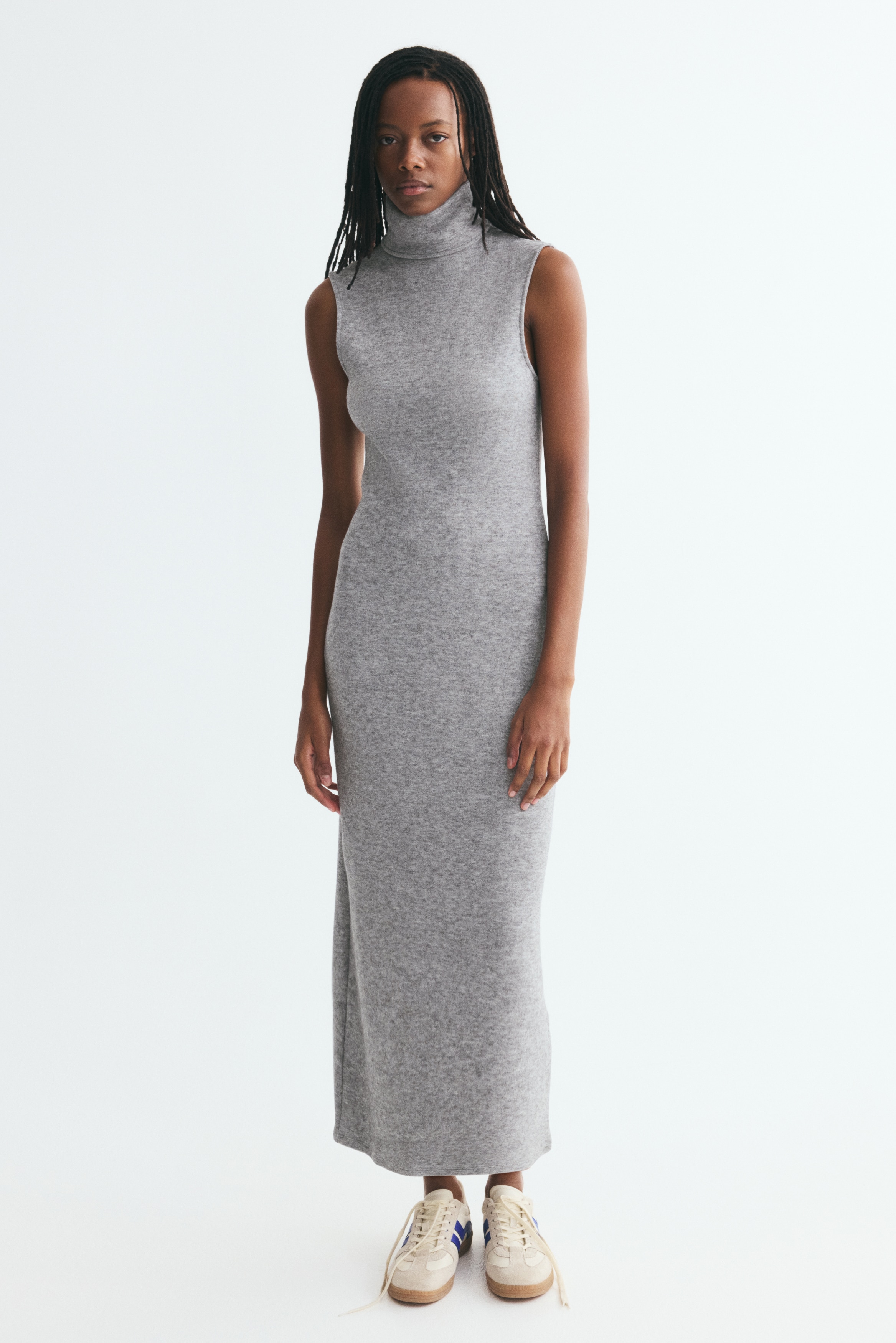 A sleeveless, heather grey knit dress is hung facing front, featuring a high turtleneck and a straight midi-length silhouette in a soft-textured marled fabric.