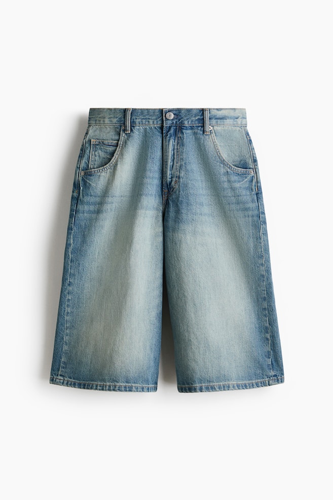 Five-pocket shorts in rigid cotton denim are presenting from the front, featuring a light blue wash with faded areas. They are designed with a regular waist, a zip fly, and a baggy fit with rounded legs, providing ample room from the seat to the hem. - 1