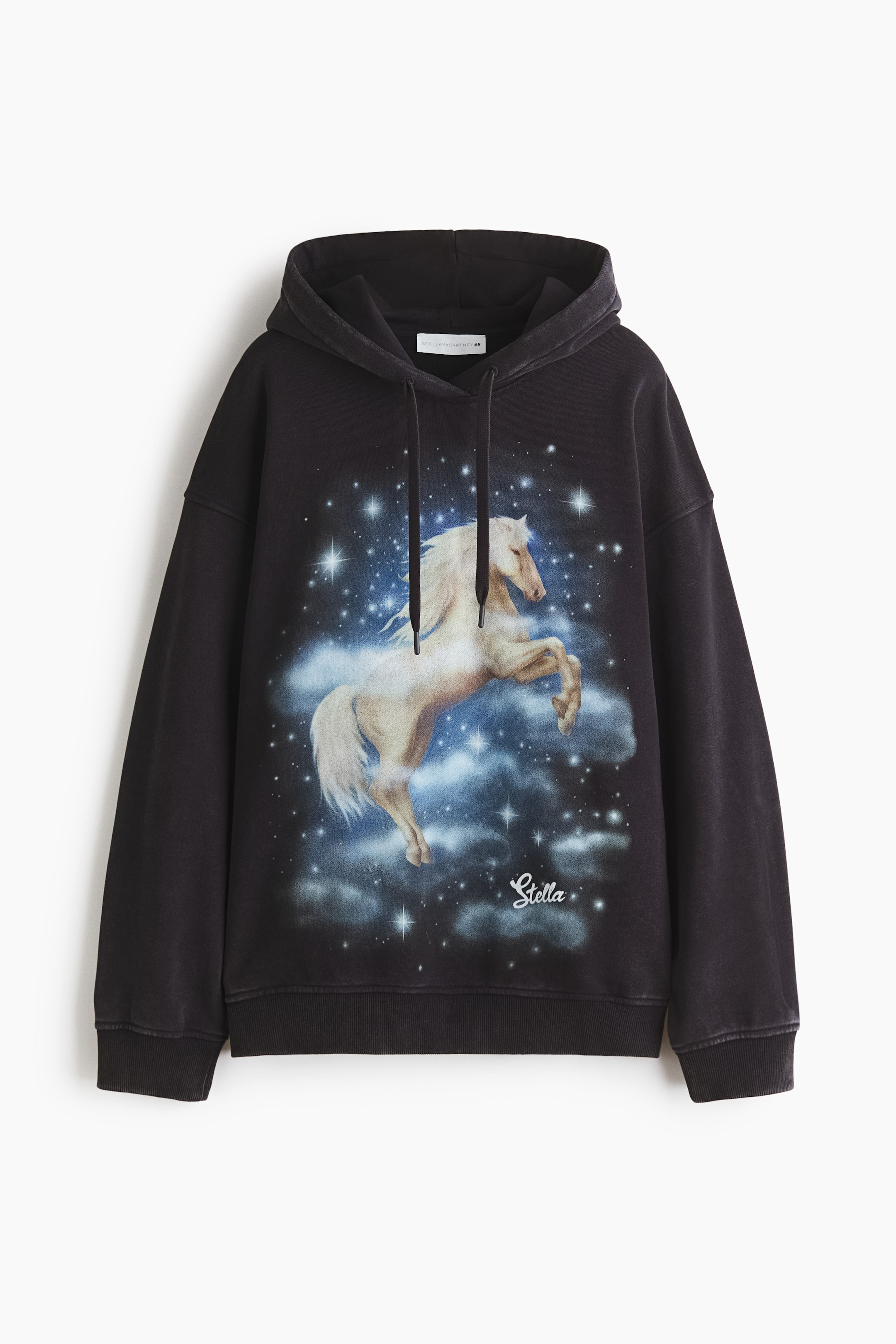 Größeres Bild ansehen: Ein schwarzer, locker sitzender Hoodie ist von vorne zu sehen und zeigt einen großen Grafikdruck auf der Brust. Der Druck zeigt ein weißes Pferd, das sich inmitten von blauen und weißen Wolken und Sternen vor einem dunklen Hintergrund aufbäumt, mit dem Wort "Stella" darunter. Er verfügt über eine doppellagige Kapuze mit Kordelzug, tief angesetzte Schultern und gerippte Bündchen und Saum.