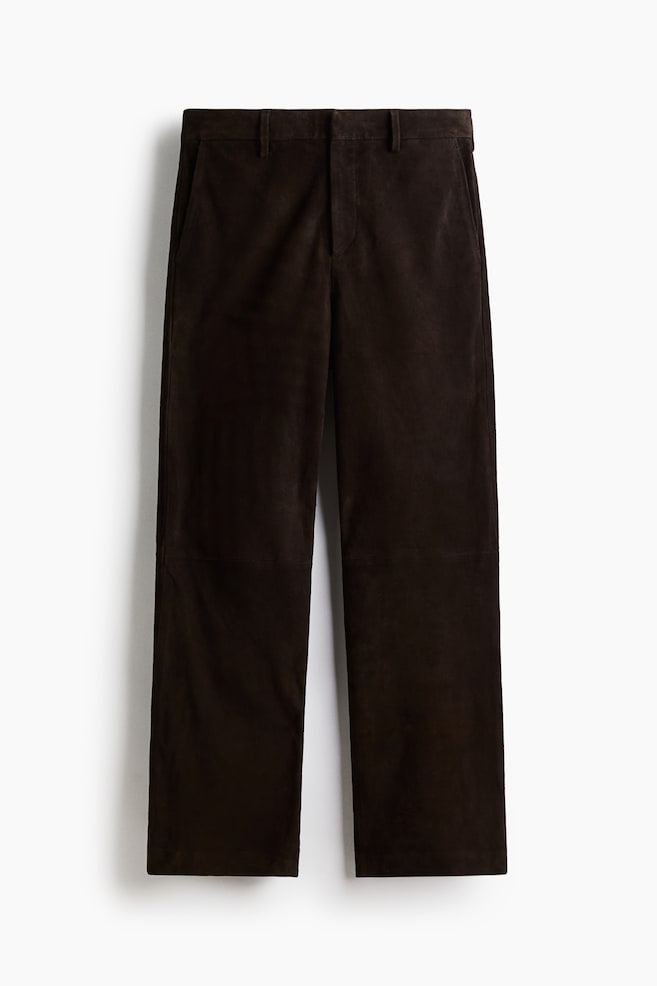 Un pantalon en daim marron foncé est posé à plat, face avant, avec un devant plat, des passants de ceinture, des poches latérales en biais et des coutures horizontales visibles sur les jambes, indiquant une construction à panneaux. - 1