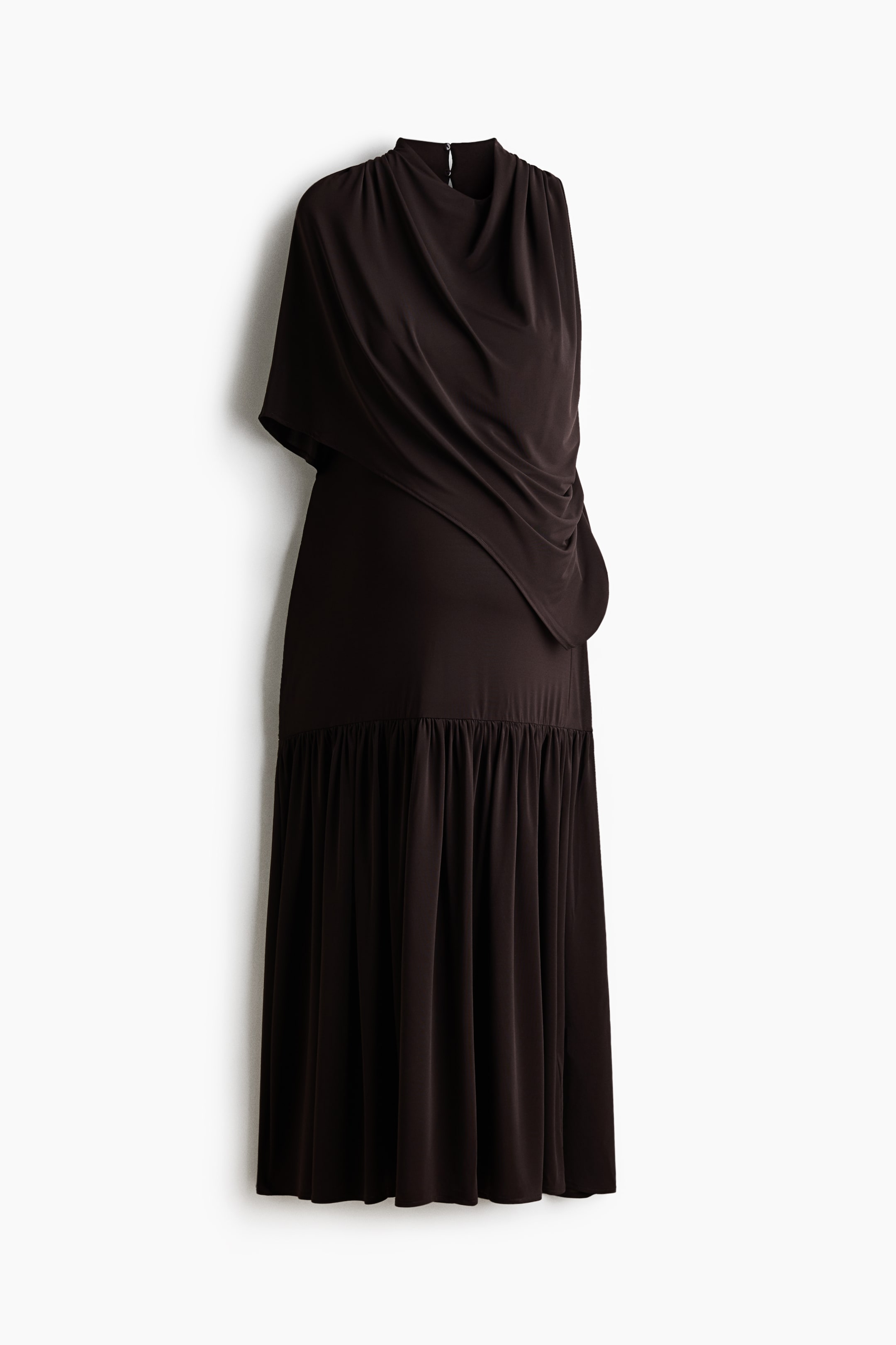 Größeres Bild ansehen: Ein langes, dunkelbraunes ärmelloses Kleid wird aus frontaler Perspektive gezeigt und verfügt über eine asymmetrische, capeartige Lage, die über eine Schulter fällt. Das Kleid präsentiert einen hohen Cowl-Ausschnitt, einen schmal geschnittenen Oberkörper und eine geraffte Stufe unterhalb der Hüfte, die in einen plissierten, fließenden Rock übergeht.