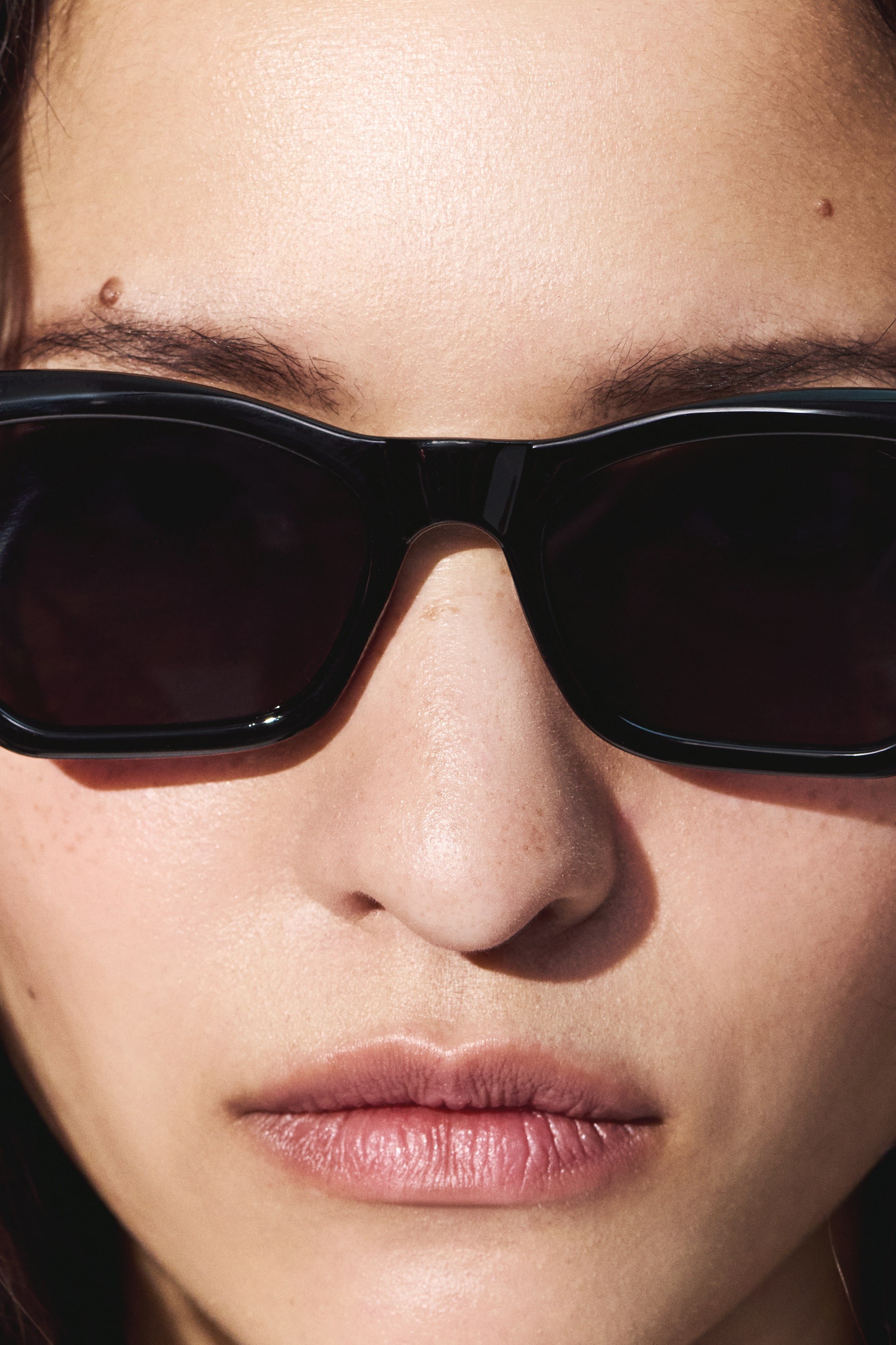 Ver imagen más grande: Se llevan gafas de sol negras, con monturas gruesas y brillantes de color negro y lentes oscuras, ajustándose perfectamente sobre el puente de la nariz.