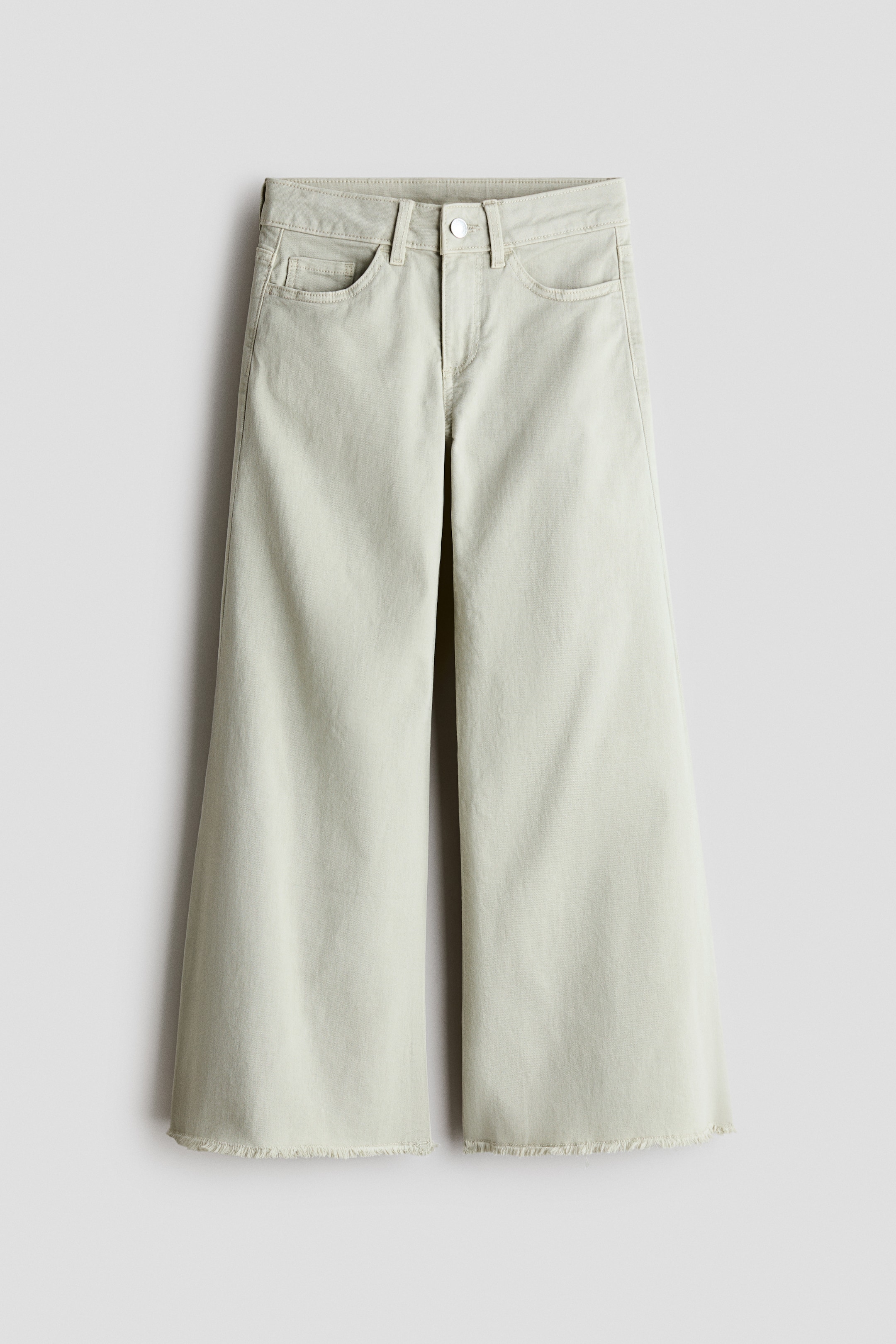 View larger image: FRONT view of light green cotton twill trousers, featuring a loose fit through the hip and thigh and wide legs. They are designed with two front pockets, a coin pocket, a button and zip fly closure, and frayed raw hems.