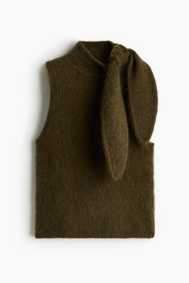 A dark olive green sleeveless knit top is presented from the front, featuring a high mock neck and a soft, fuzzy texture. Two large, rounded fabric pieces are forming a distinctive, upright shape on the right side of the collar. - 1