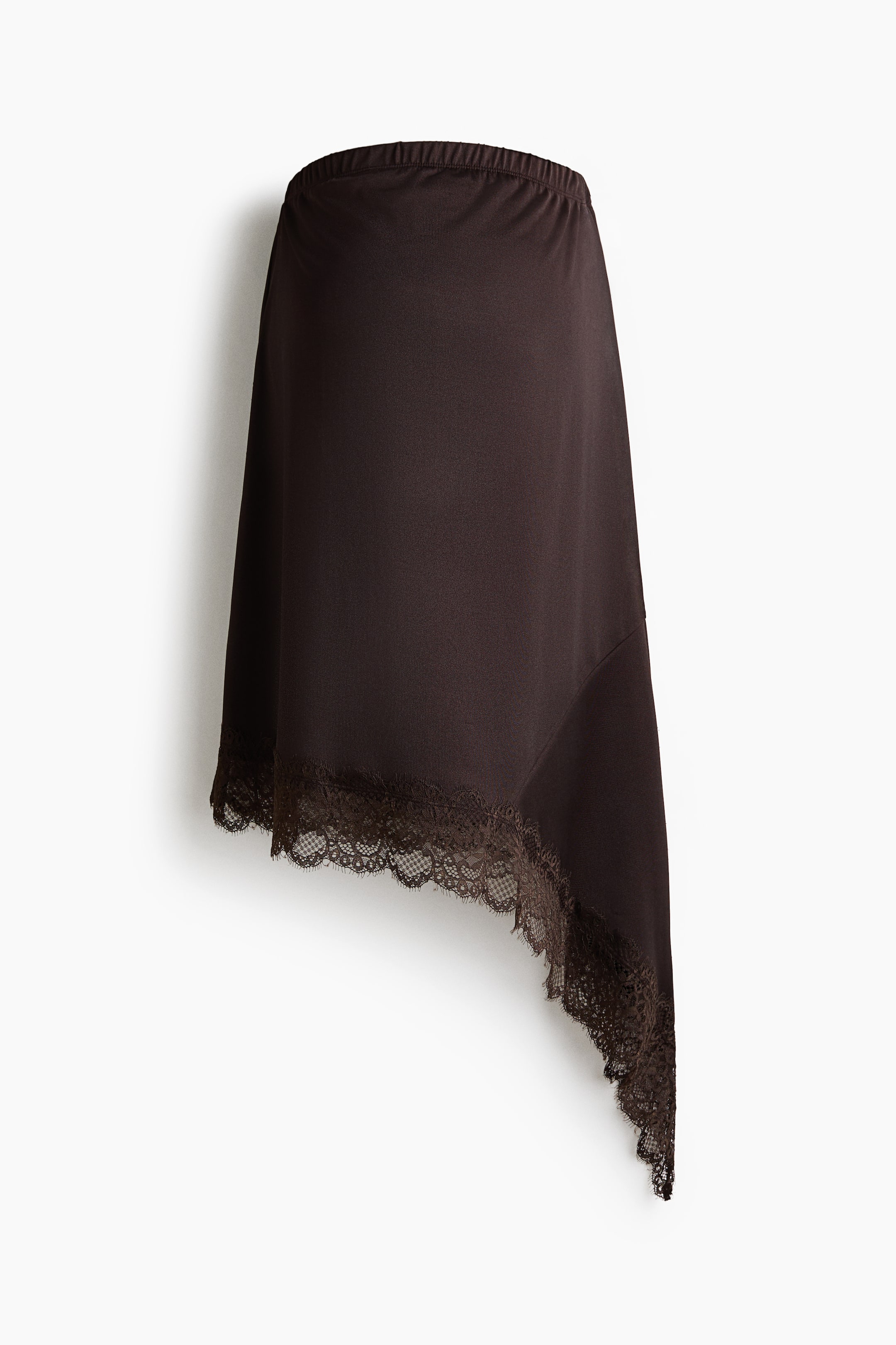 Se større billede: En mørkebrun nederdel præsenteres FORAN, med en elastisk talje og en asymmetrisk kant. Kanten er pyntet med en delikat mørkebrun blondekant.