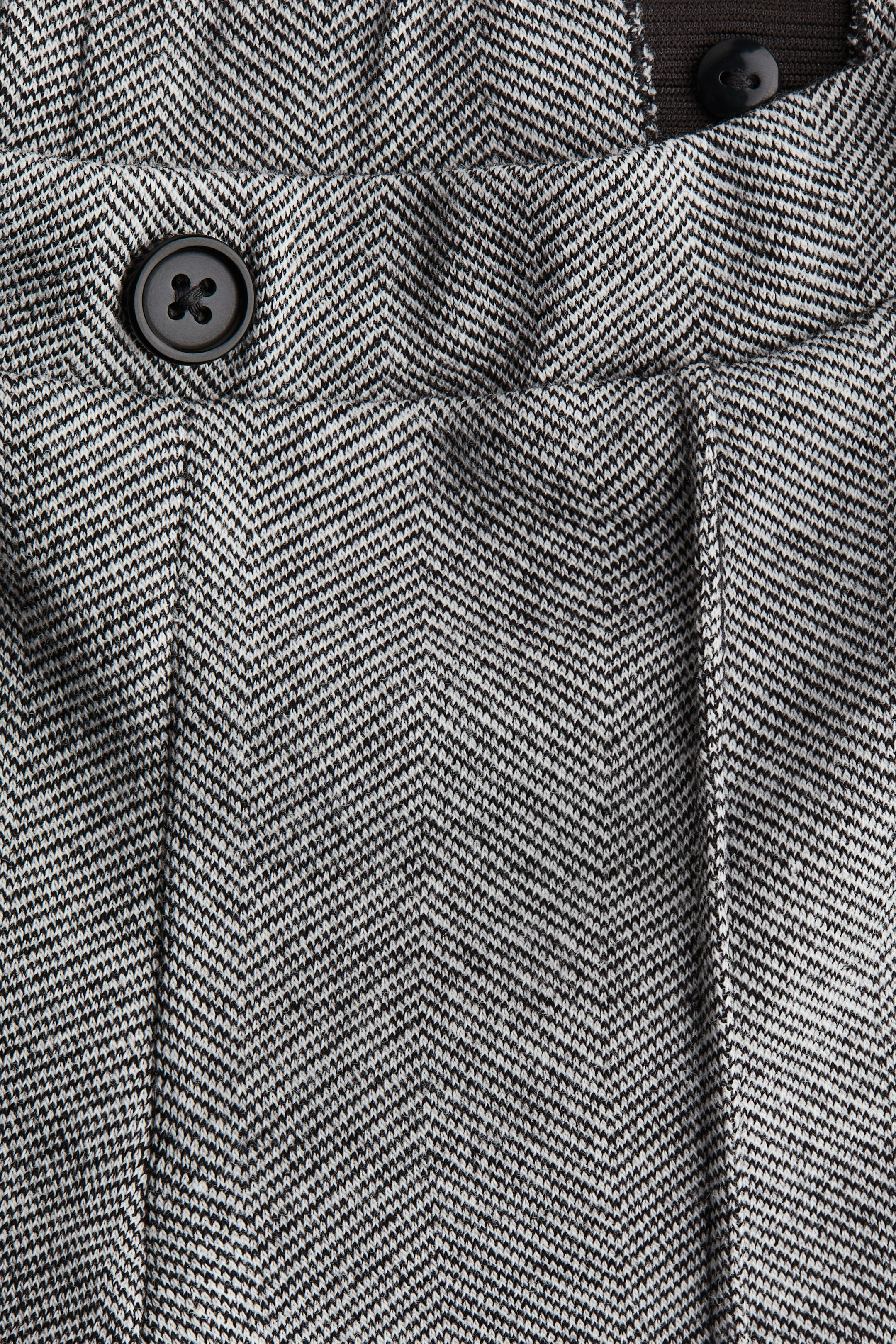 Größeres Bild ansehen: VORDERSEITE: Elegante Hosen präsentieren ein schwarz-weißes Fischgrät-Muster. Die Taille bietet eine überzogene Elastik mit sichtbaren Raffungen, einen dunklen Zierknopf und eine dezente seitliche Tascheneingriff, und vertikal eingenähte Falten verlaufen vorne.