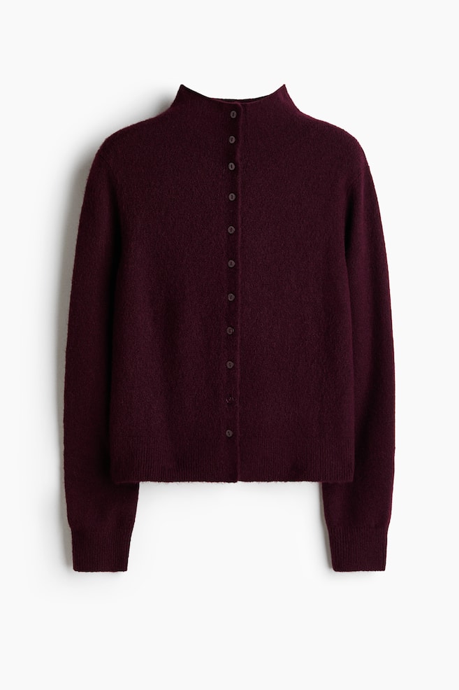Een zachte bordeauxrode gebreide cardigan met een hoge opstaande kraag en een volledige knoopsluiting aan de voorkant met kleine, donkere knopen. Het heeft lange mouwen met geribde manchetten en een geribde zoom. - 1