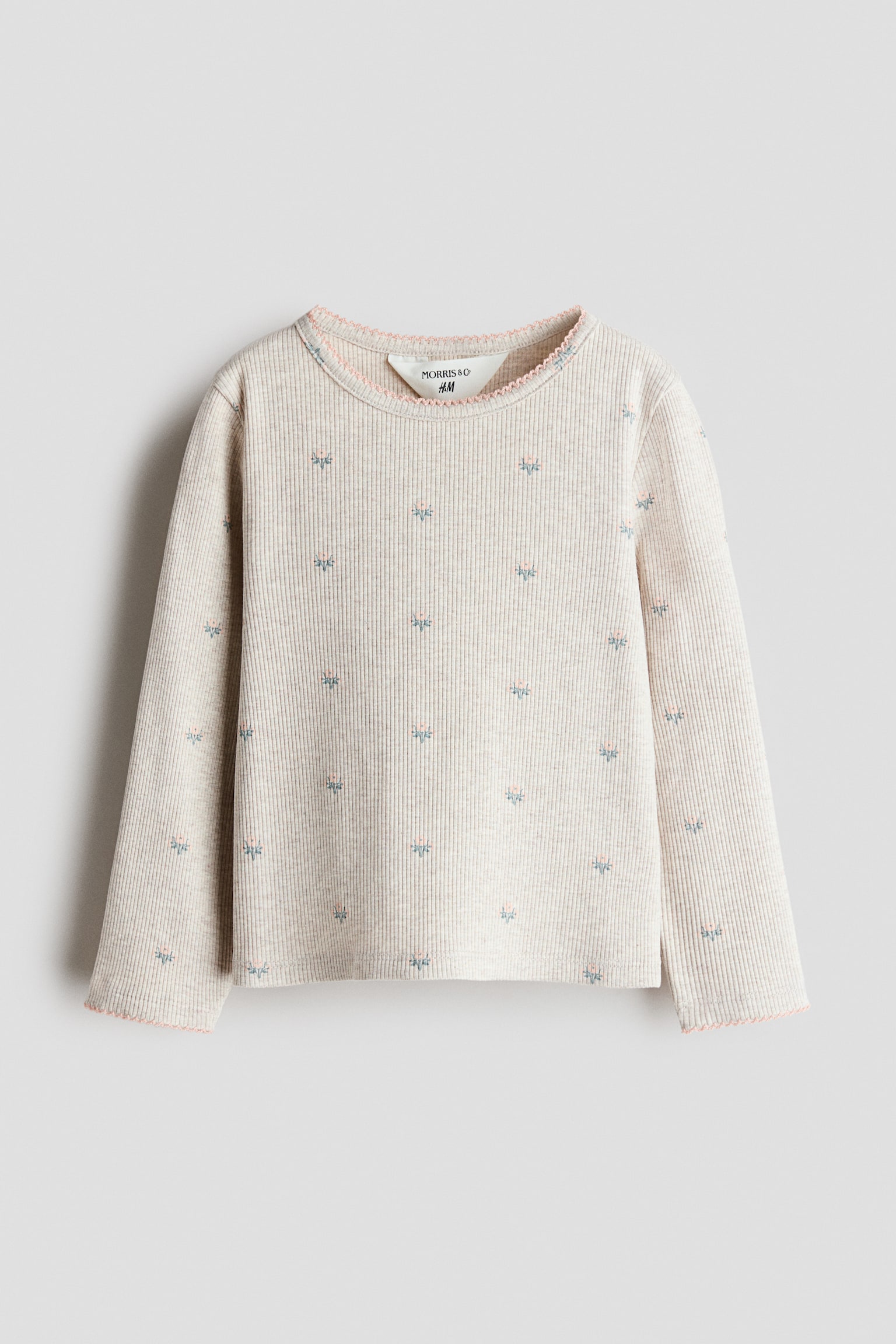 A long-sleeve top in light beige ribbed cotton jersey is shown from the front, featuring an all-over print of small, scattered floral motifs. The round neckline and long sleeve cuffs are finished with a delicate pink picot trim. - 1