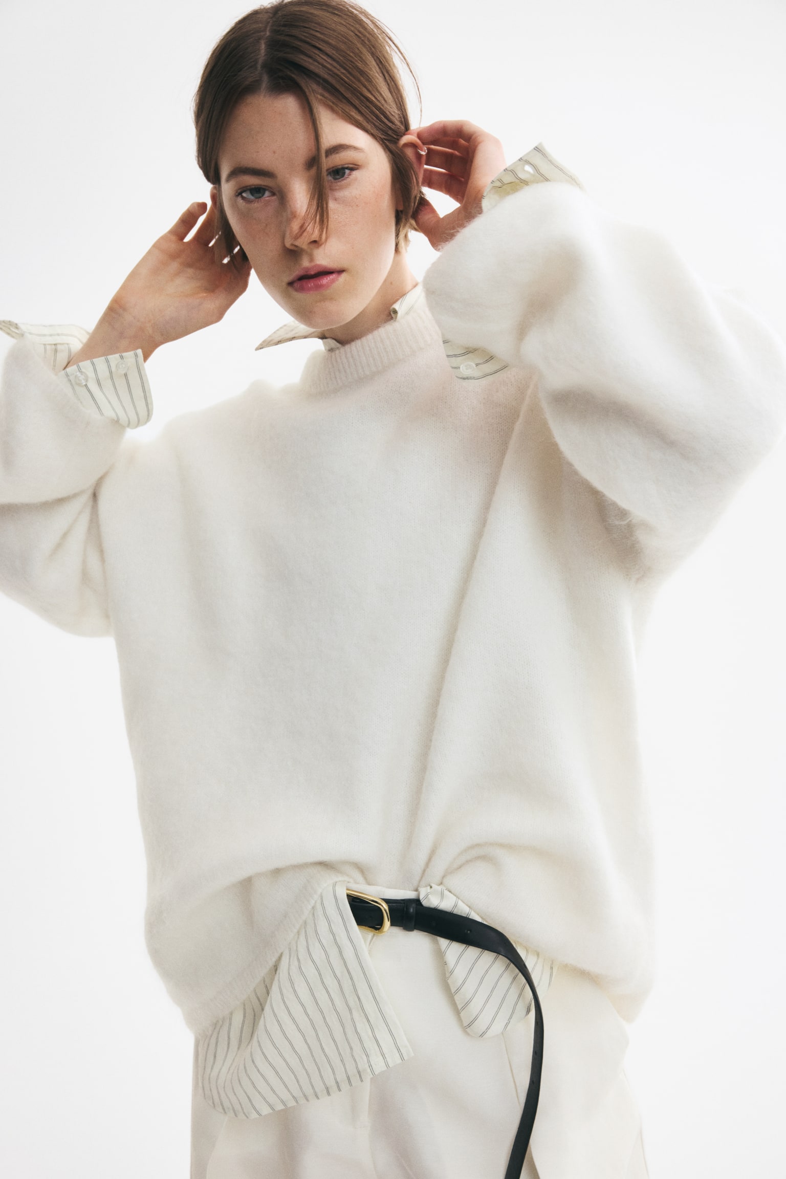 A front view of an oversized cream jumper is showcasing a soft knit with a fuzzy texture, dropped shoulders, long sleeves, and ribbing at the neckline, cuffs, and hem. - 1