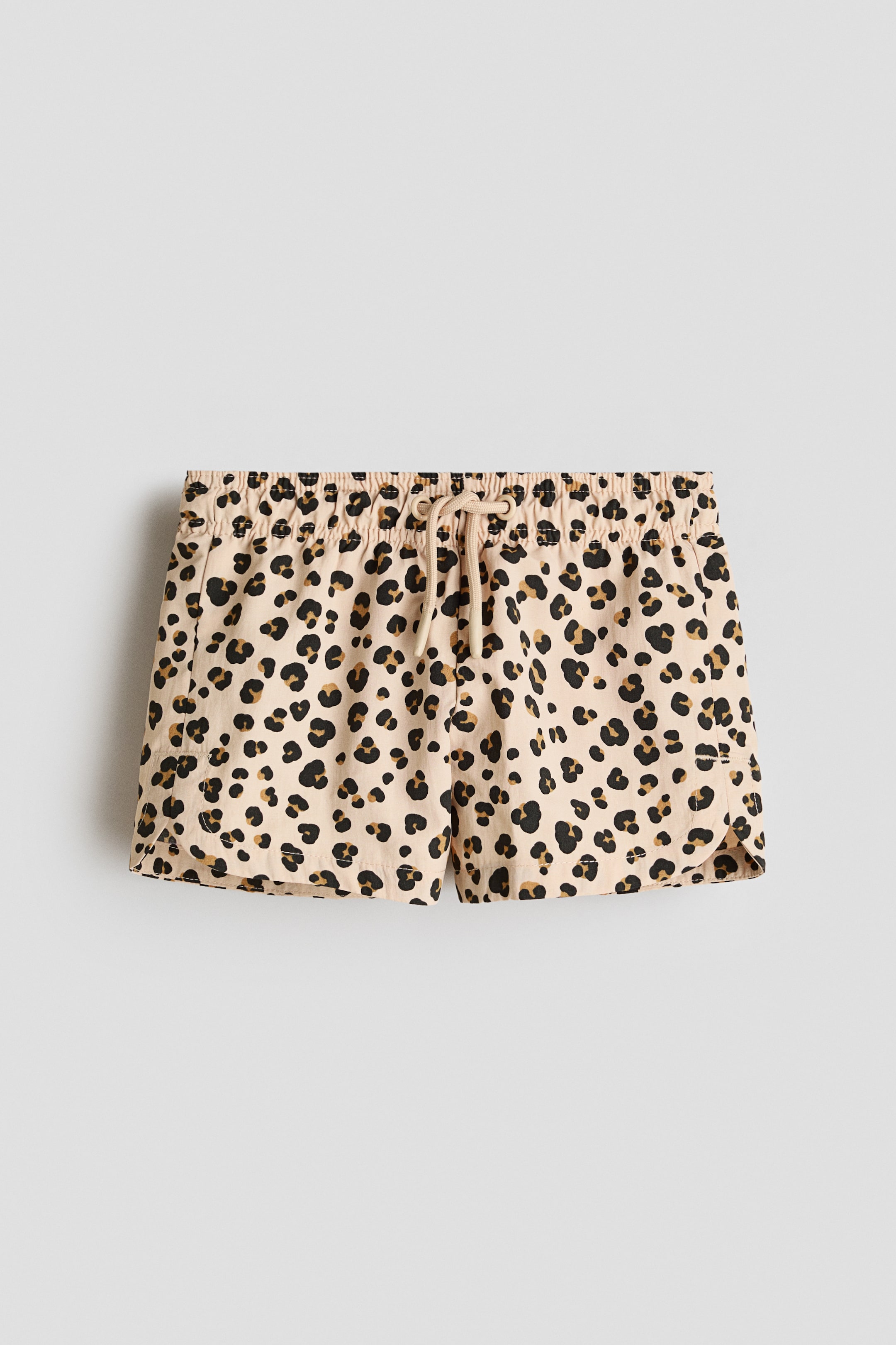 Voir une image plus grande: Les shorts de bain à motifs arborent un imprimé léopard beige, noir et brun, vus de face. Ils présentent une taille élastiquée avec cordon de serrage noué, et des ourlets légèrement arrondis avec une petite fente sur le côté.