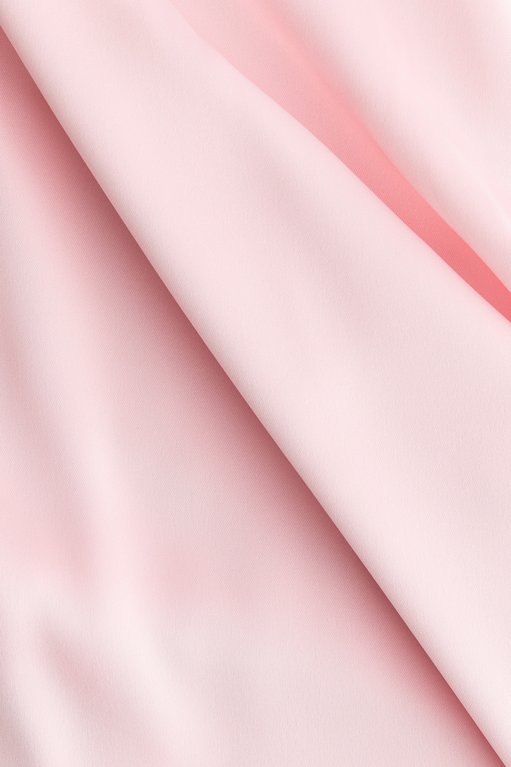 Größeres Bild anzeigen: Rosa Stoff präsentiert eine subtile, fein strukturierte Oberfläche. Er faltet sich diagonal über das Bild, wodurch weiche Drapierungen und unterschiedliche Rosatöne entstehen.