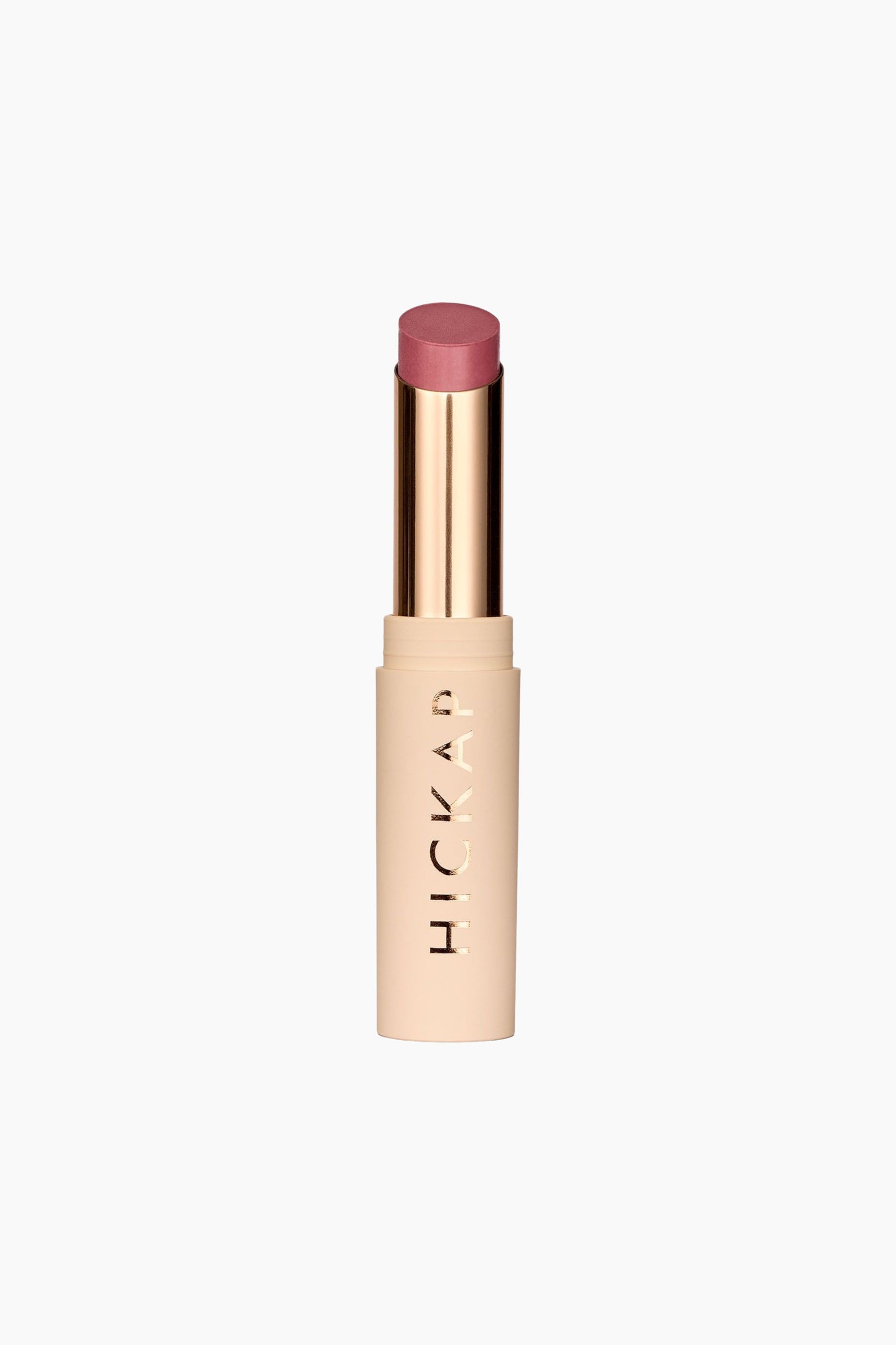 Visa större bild: Plush Pout Lipstick står upprätt och visar upp ett dammigt rosarosa läppstift i en metallisk guldfärgad innertub. Den cylindriska basen är i en matt beige nyans och har varumärkesnamnet "HICKAP" tryckt vertikalt i reflekterande guldfärgade bokstäver.