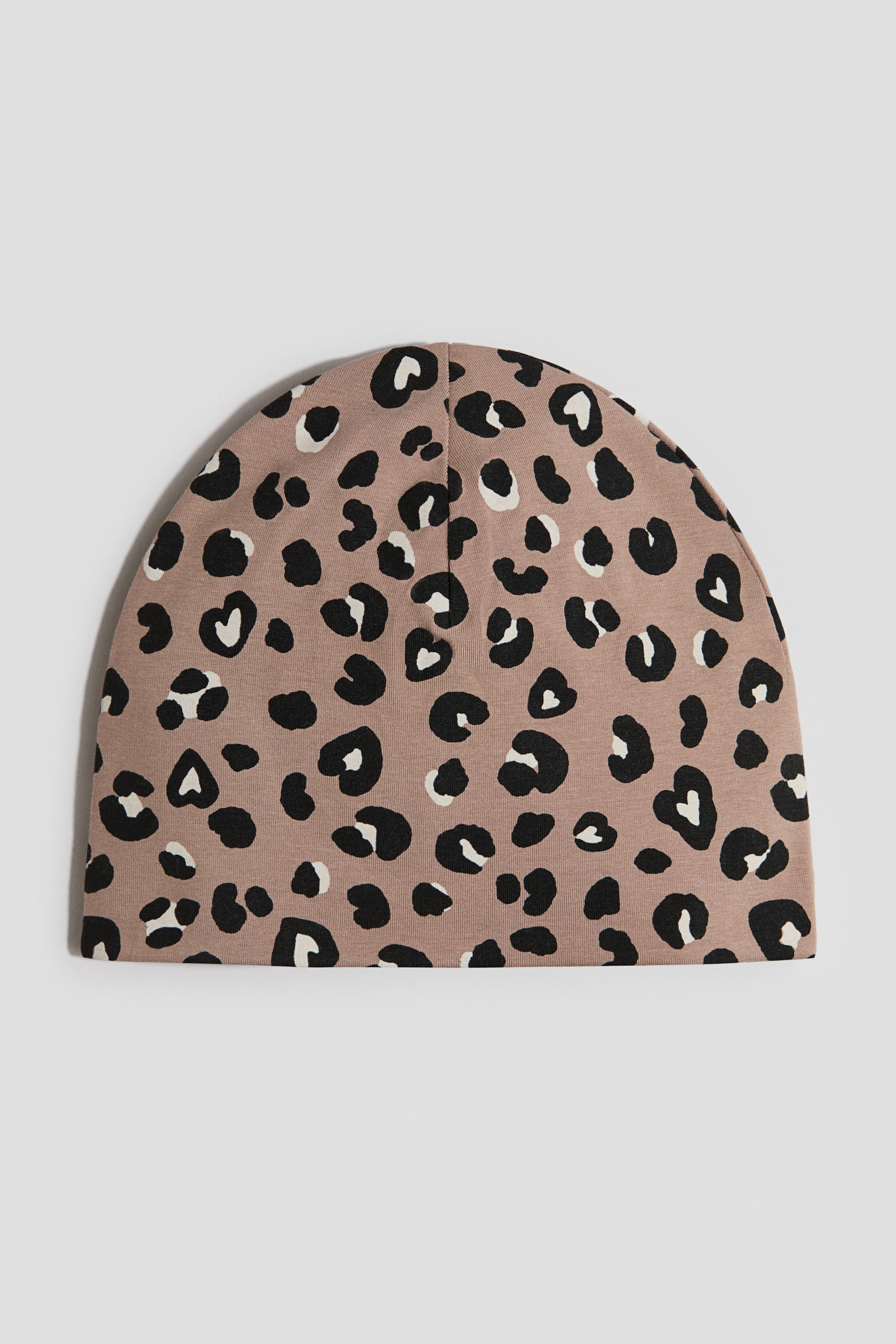 Zobrazit větší obrázek: Čepice beanie má světle hnědý základ s černobílým leopardím vzorem. Uprostřed vrchní části kupolovité čepice vede centrální šev.