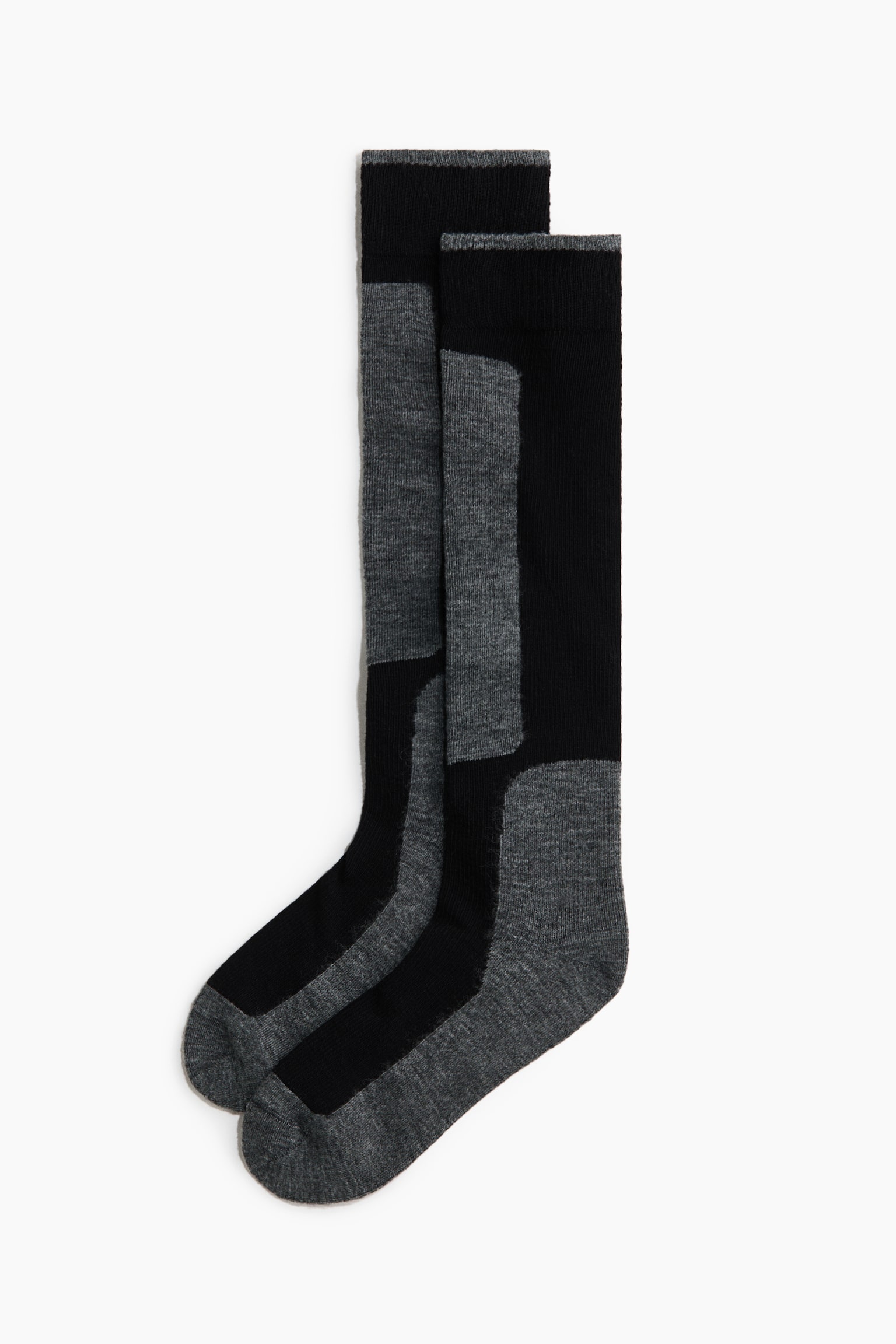 Èosetele pânÄ la genunchi sunt aÈezate întinse Èi suprapuse într-o vedere de profil, afiÈând un design color-block în negru Èi gri melanj. Èosetele au manÈete ribbate cu o margine subÈire gri, un panou gri de-a lungul tibiei Èi zone contrastante gri la cÄlcâi Èi vârf.