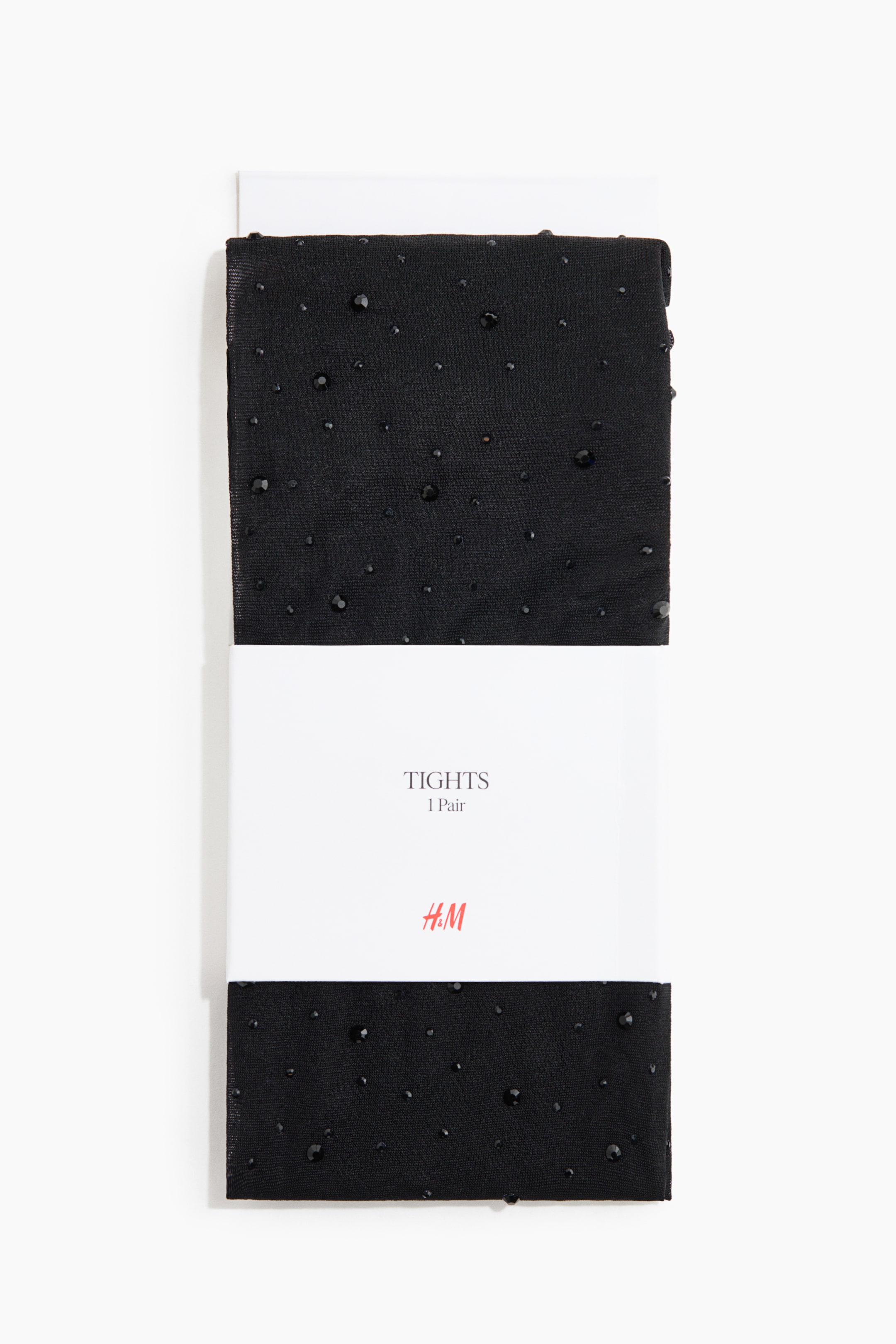 Ampliar la imagen: Un par de medias negras dobladas con pedrería negra brillante dispersa se presenta de frente. Las medias están envueltas con una banda de empaque de papel blanco que muestra el texto "TIGHTS 1 Pair" y un logotipo rojo.