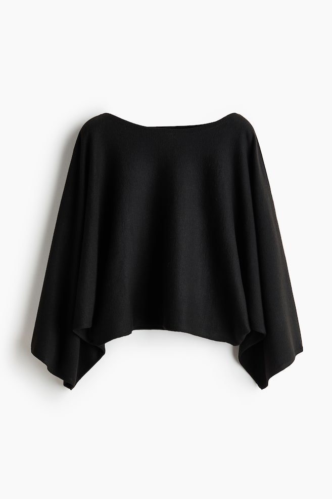 A short, loose-fit black knit top is hanging facing front, featuring a wide boat neckline and long cape sleeves that are draping down the sides. - 1