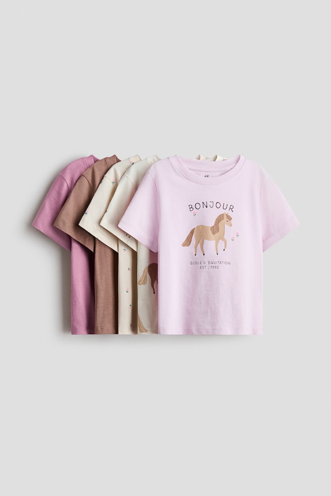A stack of t-shirts in various colours and soft cotton jersey is displaying their front views, each featuring short sleeves and a ribbed trim around the neckline. - 1