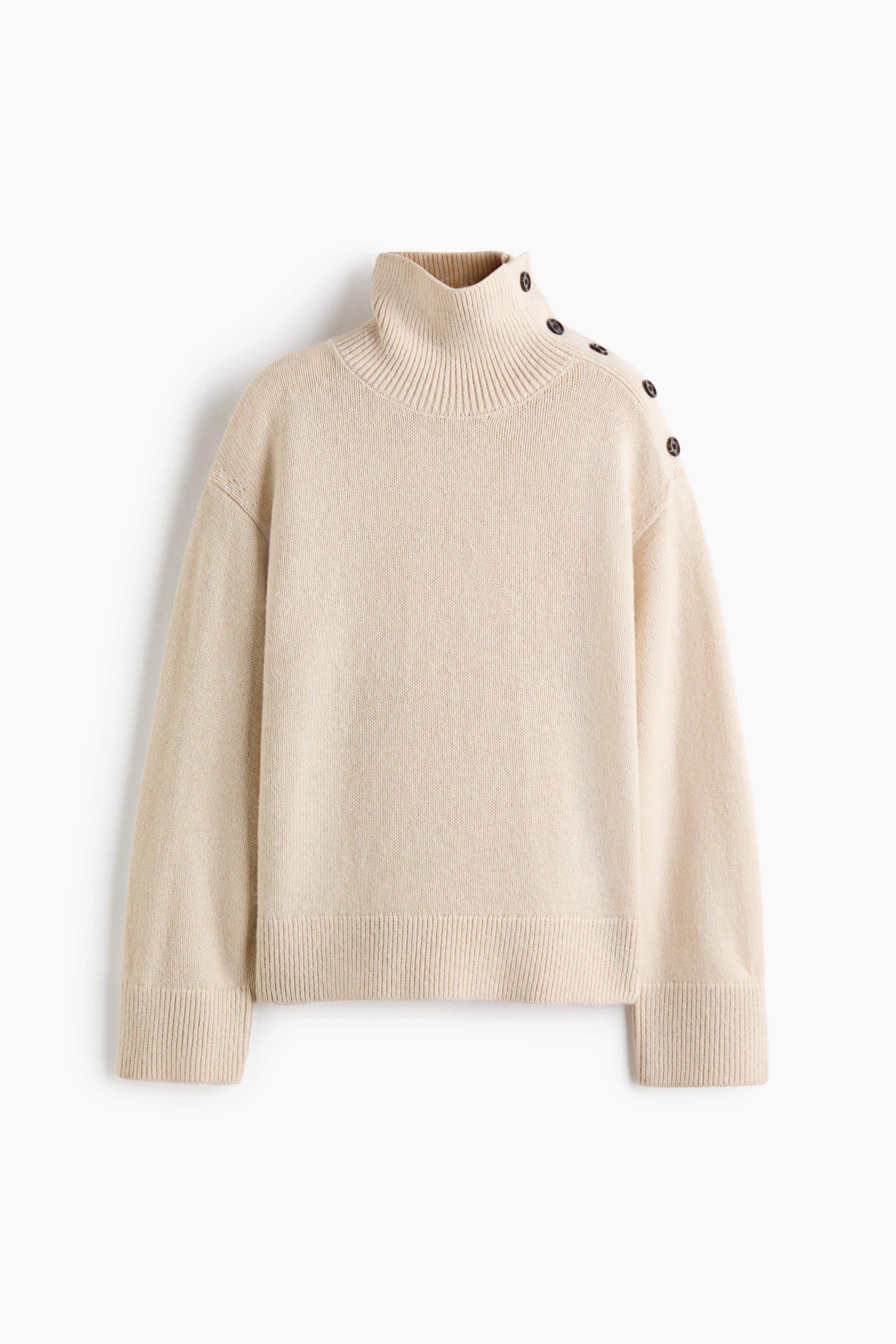 Ver imagen más grande: Un jersey de punto color crema visto de frente, con cuello alto de canalé y tapeta diagonal con botones a lo largo del hombro izquierdo. El jersey presenta hombros caídos, mangas largas con puños anchos de canalé y bajo acanalado a juego.