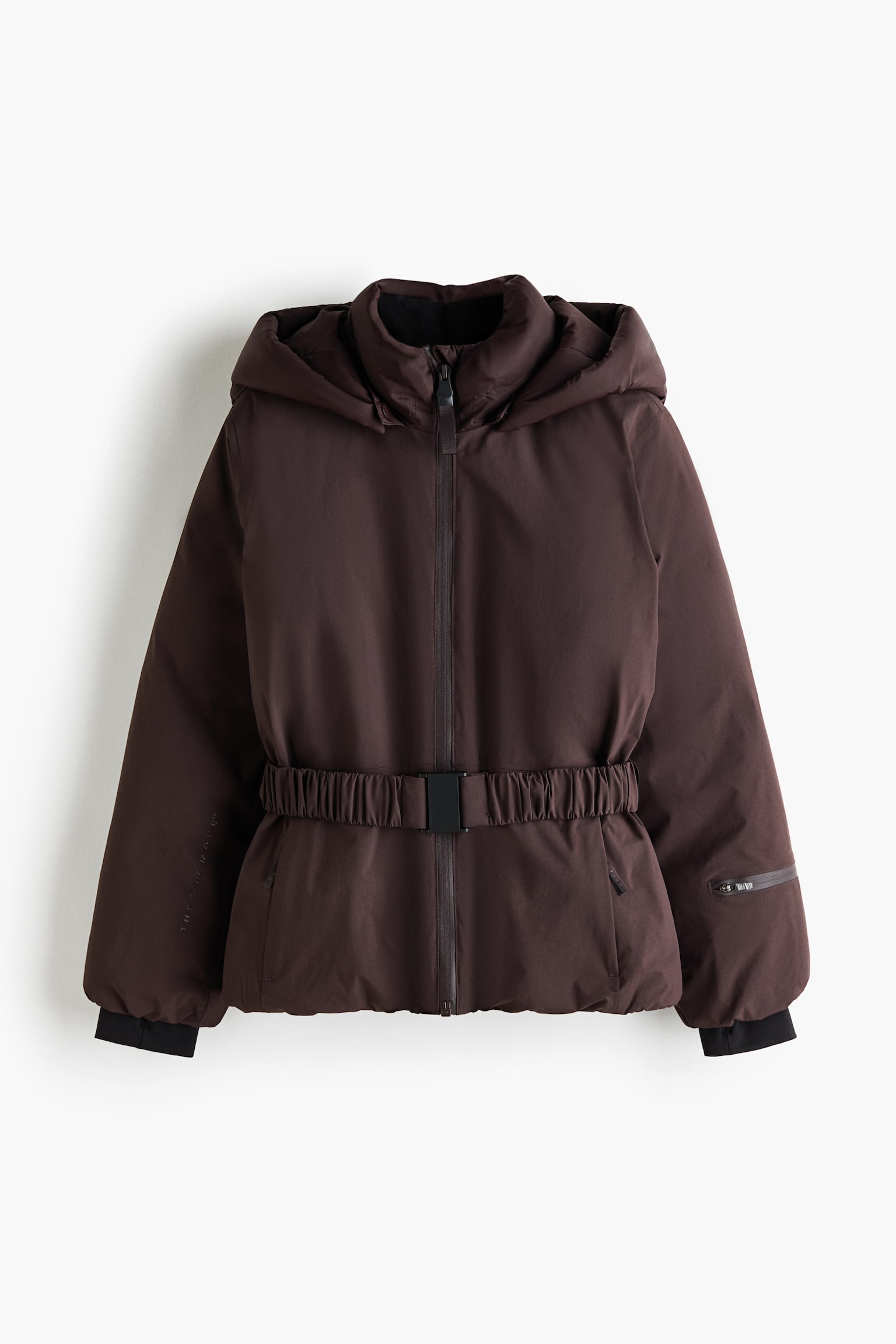 Eine dunkelbraune Skijacke mit Kapuze ist von vorne zu sehen und verfÃ¼gt Ã¼ber einen elastischen Taillenbund mit schwarzer Schnalle. Die Jacke ist mit einem hohen Kragen, einem durchgehenden FrontreiÃverschluss und langen Ãrmeln gestaltet, die an den Handgelenken mit schwarzen, innenliegenden SturmabschlÃ¼ssen enden; auÃerdem befindet sich am linken Unterarm eine kleine ReiÃverschlusstasche.