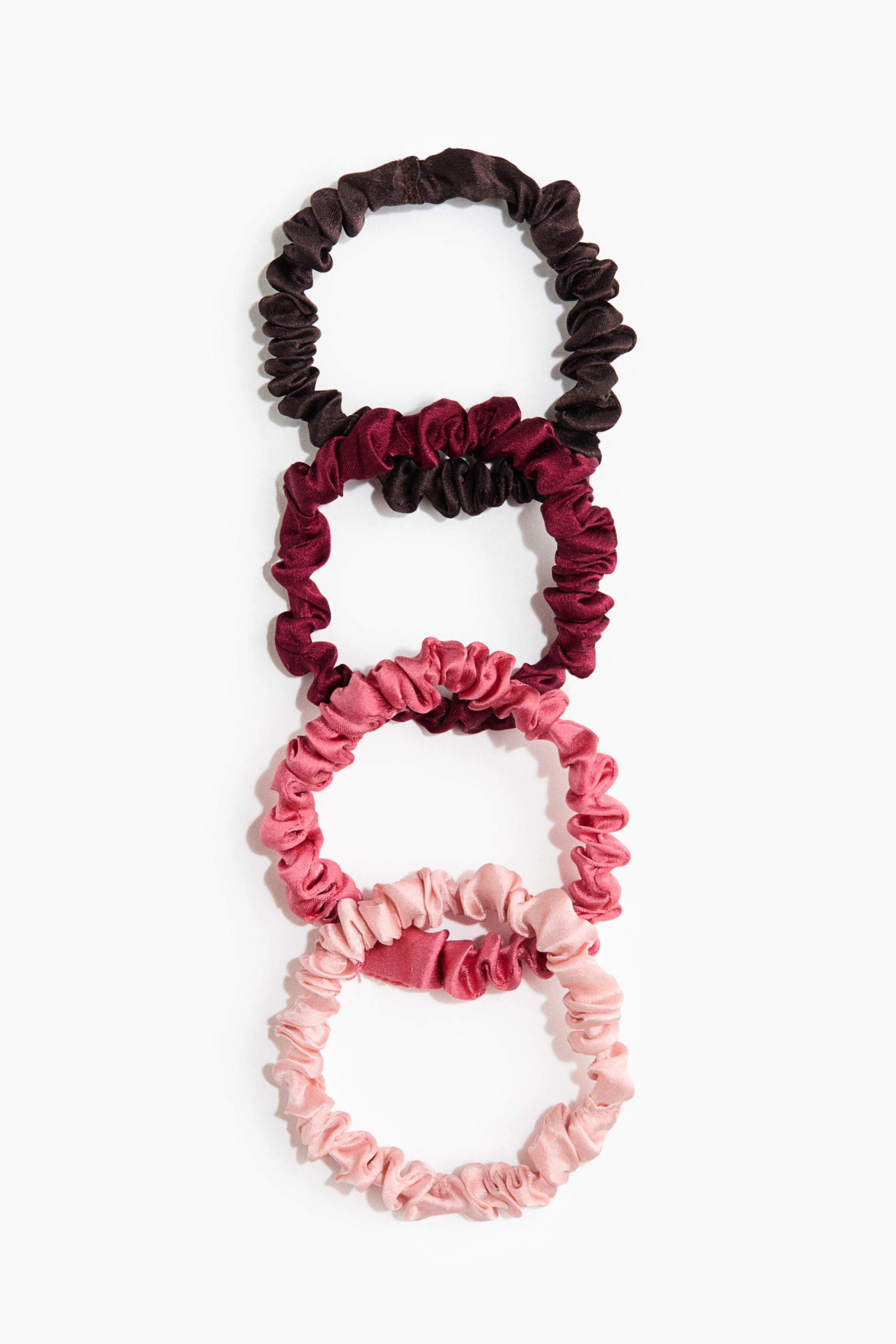 Visualizza immagine più grande: Cinque elastici per capelli, realizzati in seta di gelso lucente, sono disposti in piano e impilati verticalmente, mostrando un gradiente di colore che va dal marrone scuro e bordeaux in alto a varie sfumature di rosa verso il basso. Ogni elastico mette in risalto la sua texture arricciata e increspata, con quello rosa chiaro in fondo caratterizzato da un piccolo dettaglio di fascia piatta.