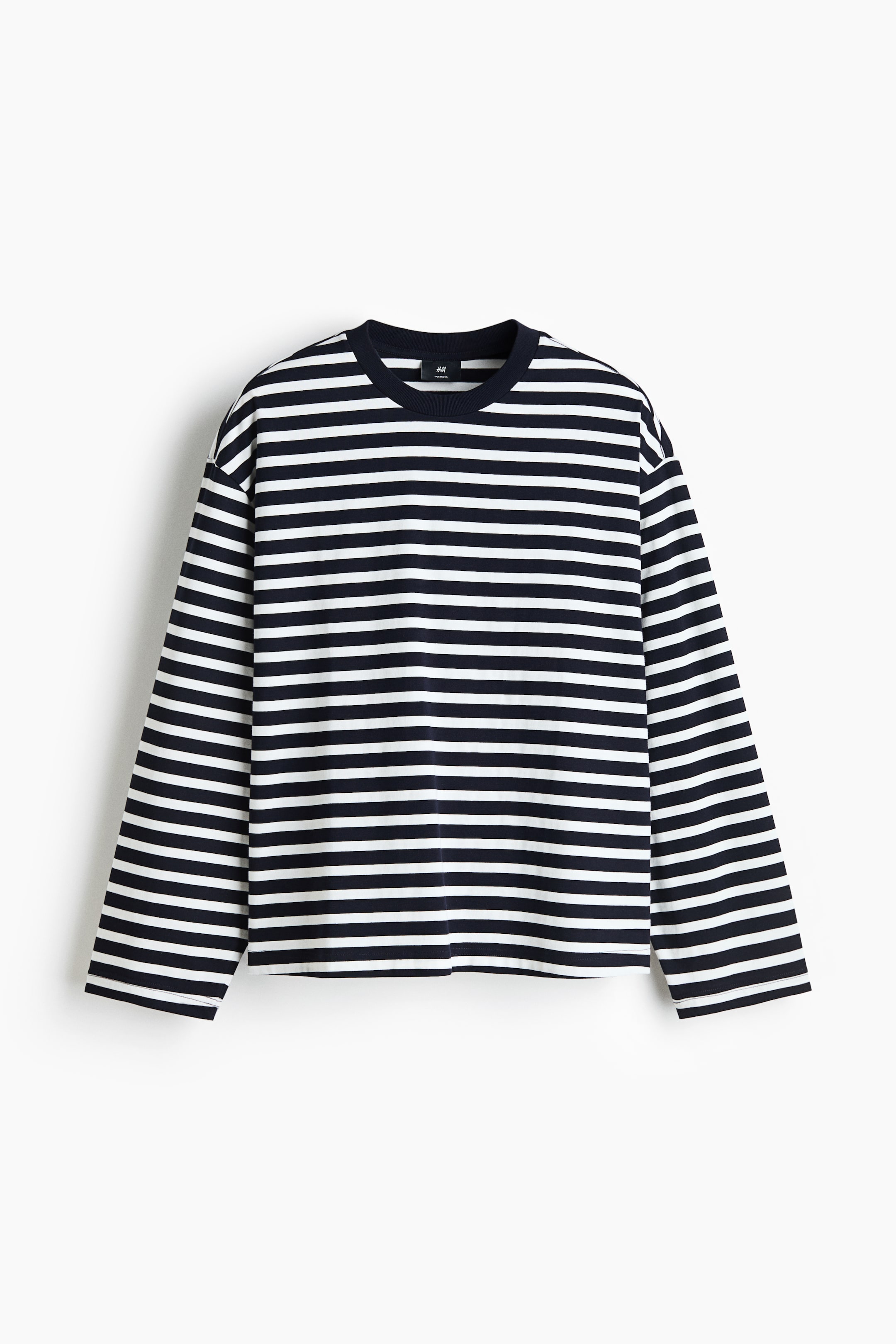 Größeres Bild ansehen: Ein Langarmshirt aus schwerem Jersey ist von vorn zu sehen und zeigt ein horizontales schwarz-weißes Streifenmuster. Das Shirt präsentiert sich in einer Oversize-Silhouette mit überschnittenen Schultern, einem einfarbigen, dunkel gerippt eingefassten Rundhalsausschnitt und einem geraden Saum.