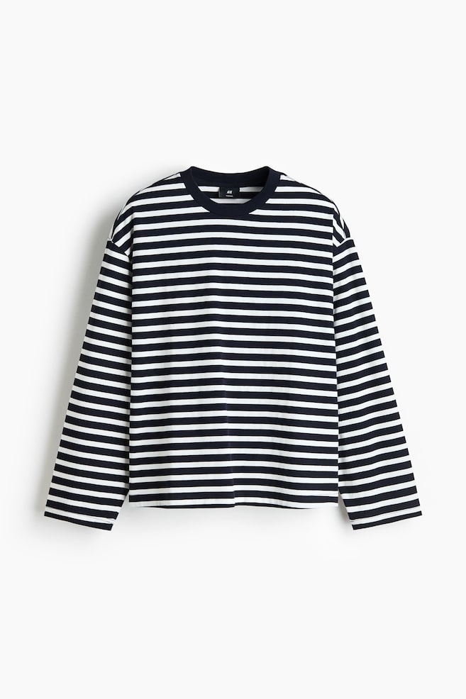 Un haut Ã  manches longues en jersey Ã©pais est prÃ©sentÃ© de face, avec un motif Ã  rayures horizontales noires et blanches. La chemise affiche une silhouette oversize avec des Ã©paules tombantes, un col rond uni foncÃ© Ã  bord-cÃ´te et un ourlet droit. - 1