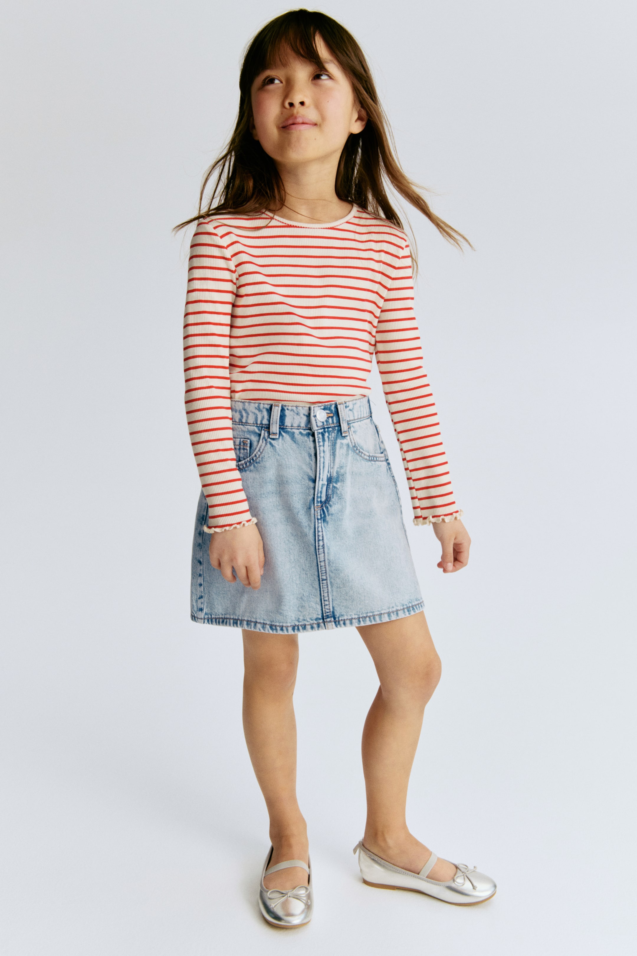 View larger image: The 5-pocket skirt in washed cotton denim is shown from the front, showcasing a light blue hue with faded sections. It includes a button closure, a zip fly, two front pockets, and a coin pocket, all set on a classic denim waistband.