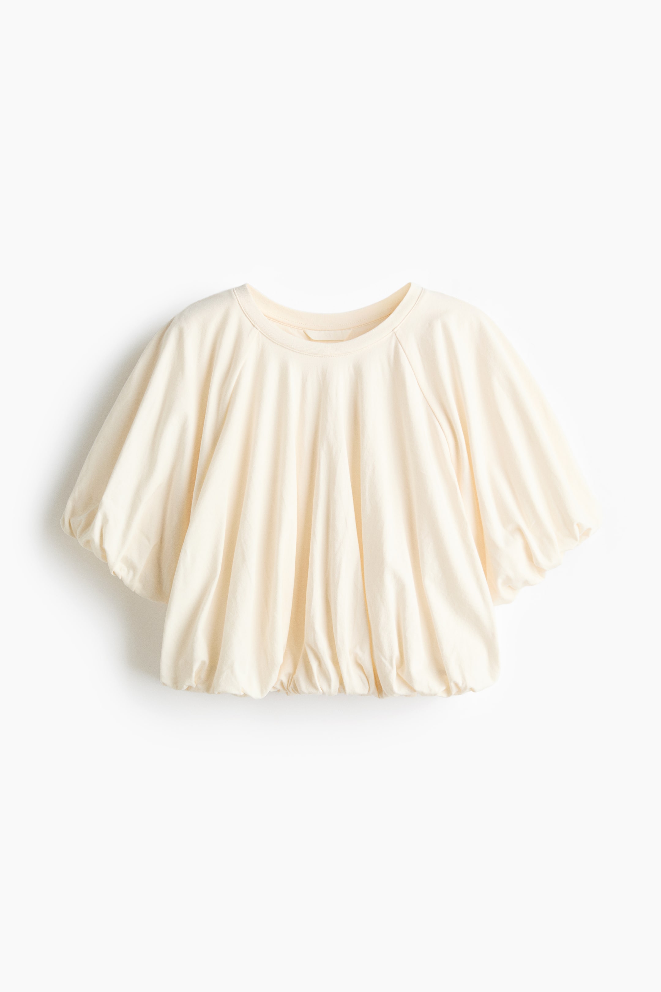 View larger image: A cream-coloured top featuring a round neck, raglan puff sleeves, and a gathered hem that creates a blouson silhouette.