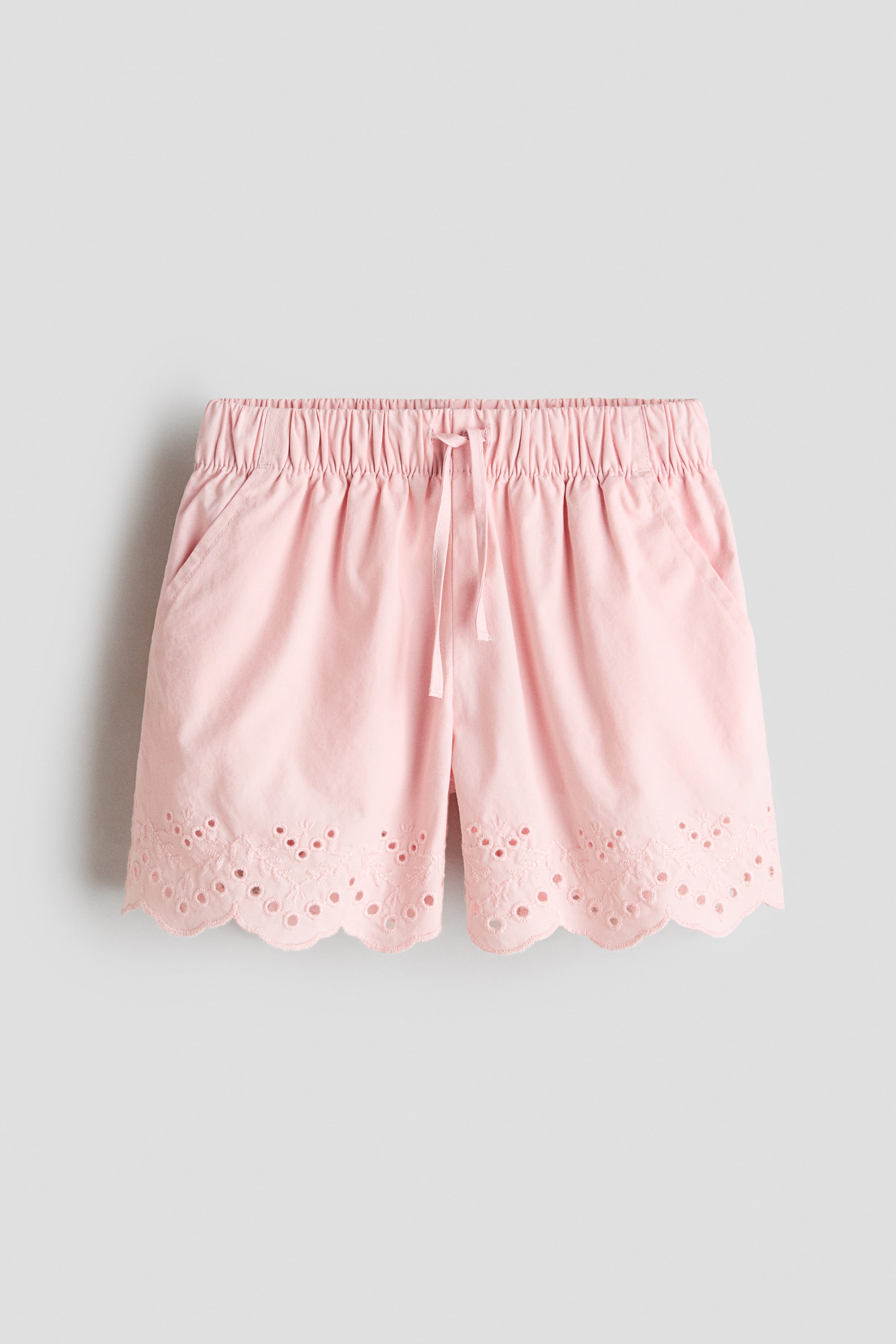 Grösseres Bild ansehen: Rosa Shorts mit einem elastischen, gerafften Bund und einem Kordelzug vorne, sowie schrägen Seitentaschen. Die Shorts sind mit einem gewellten Saum abgeschlossen, der Broderie Anglaise Stickerei präsentiert.