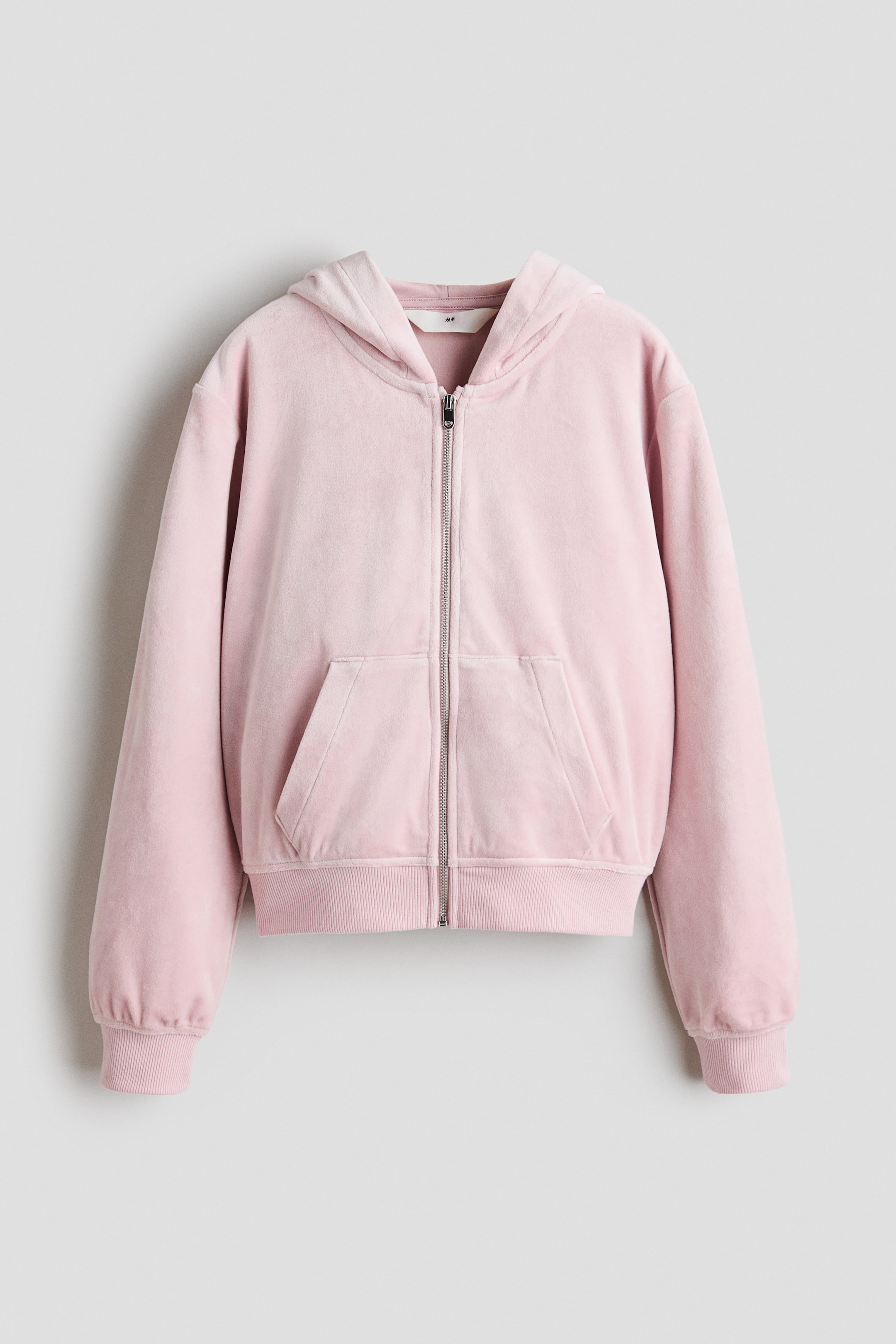View larger image: A pink velour full-zip hoodie is shown from the front, featuring a hood, a silver-toned zipper, two patch pockets, ribbed cuffs, and a ribbed hem.