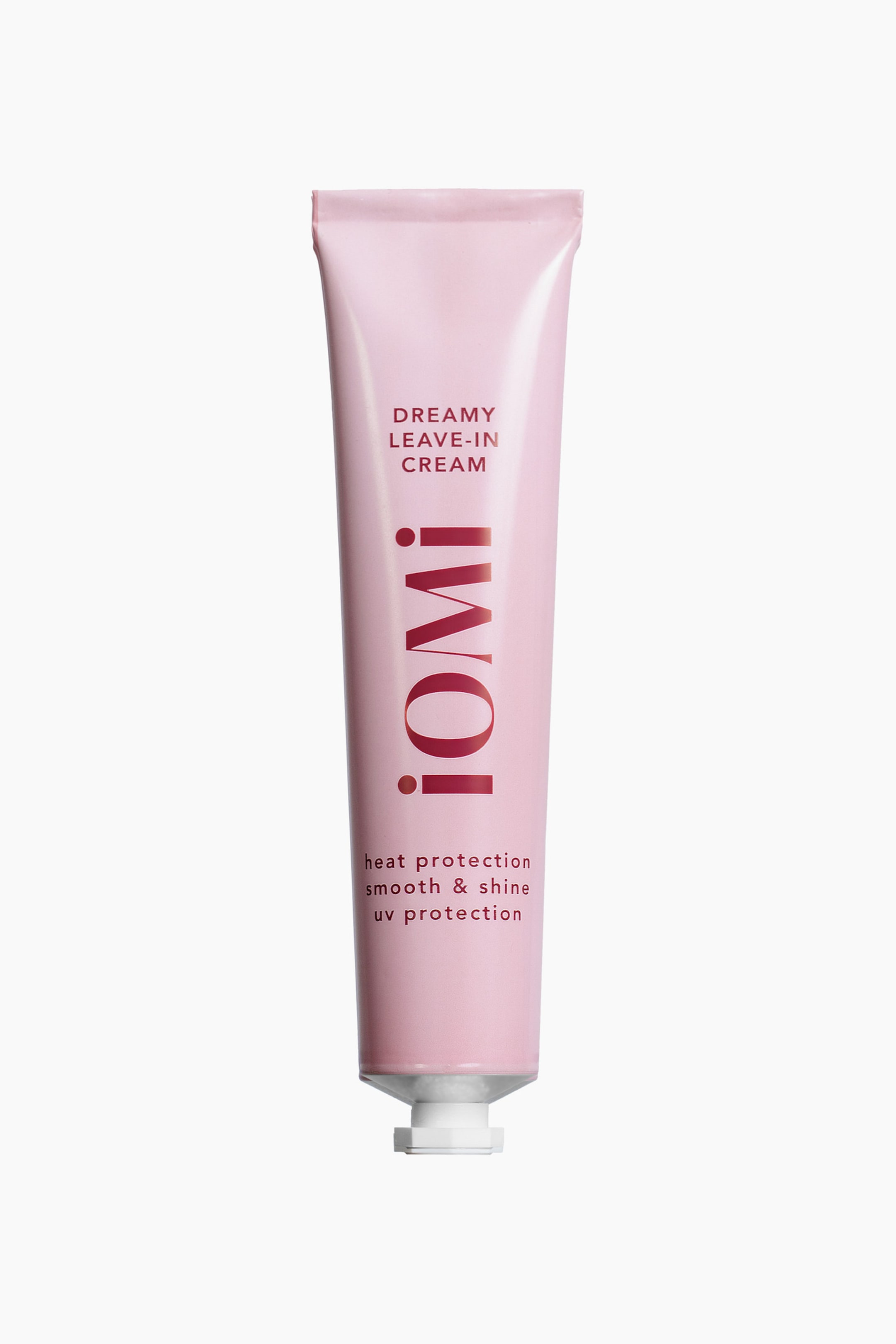 Visa större bild: En rosa tub av leave-in-kräm står upprätt, vänd framåt. Tuben visar "DREAMY LEAVE-IN CREAM" högst upp, "iOMi!" vertikalt i mitten, och "värmeskydd slät & glans UV-skydd" längst ner, allt i röd text. En vit dispenserkork är synlig vid basen.