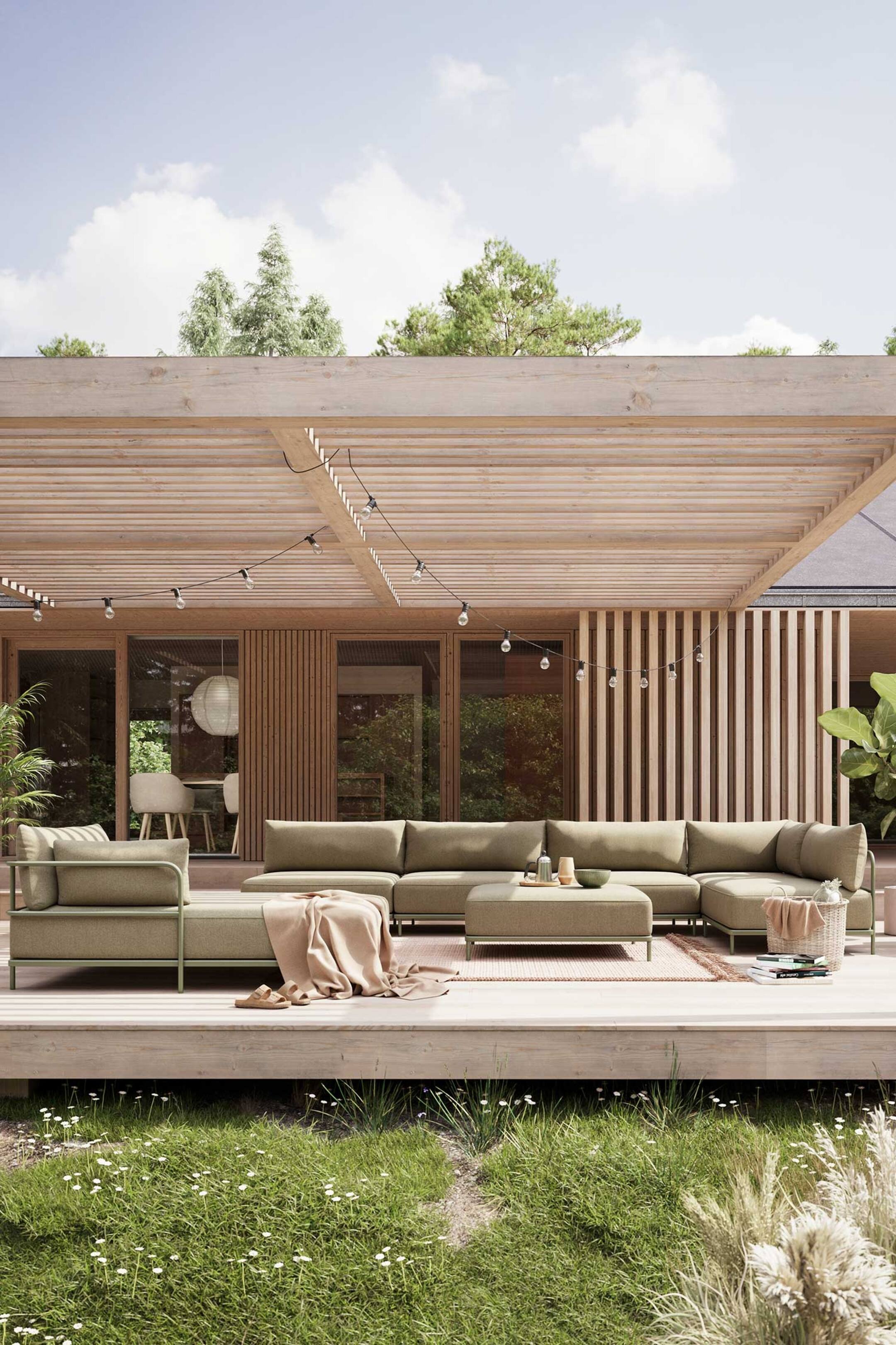 Größeres Bild ansehen: Ein olivgrünes modulares Outdoor-Sofa mit passendem quadratischem Hocker ist aus einem front-rechten Winkel zu sehen und zeigt seine L-förmige Konfiguration sowie den schlanken, dezent grünen Metallrahmen. Es verfügt über dicke Sitz- und Rückenkissen, mit einer hellrosa Decke, die über die Chaiselongue drapiert ist, und einem kleinen Tablett mit einer Flasche und Schalen, die auf dem Hocker ruhen.