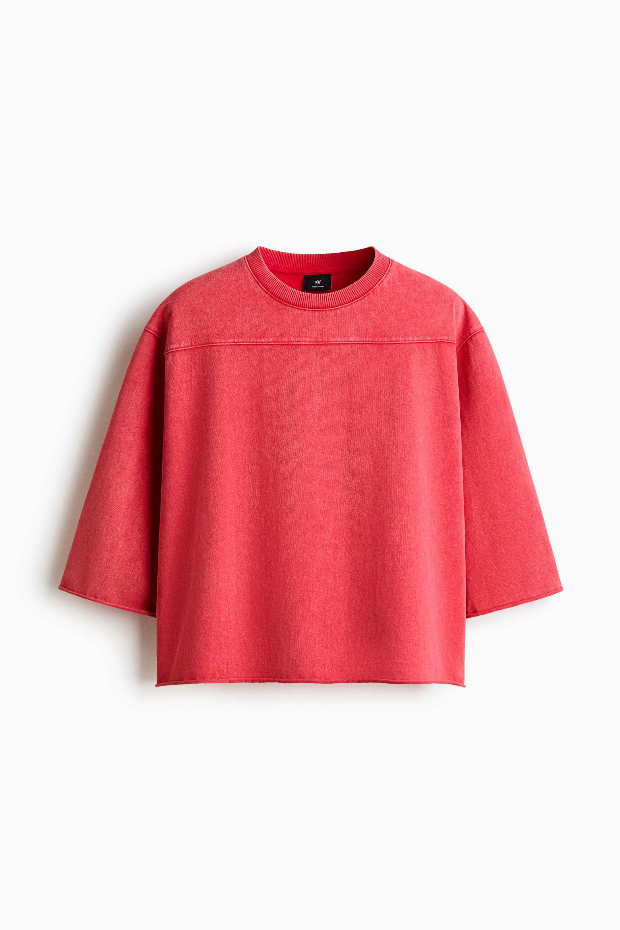 View larger image: A red, heavyweight cotton jersey boxy-style t-shirt is shown from the front, featuring a round, rib-trimmed neckline, dropped shoulders, and a yoke across the chest. Raw edges at the cuffs and hem create an oversized, baggy silhouette.