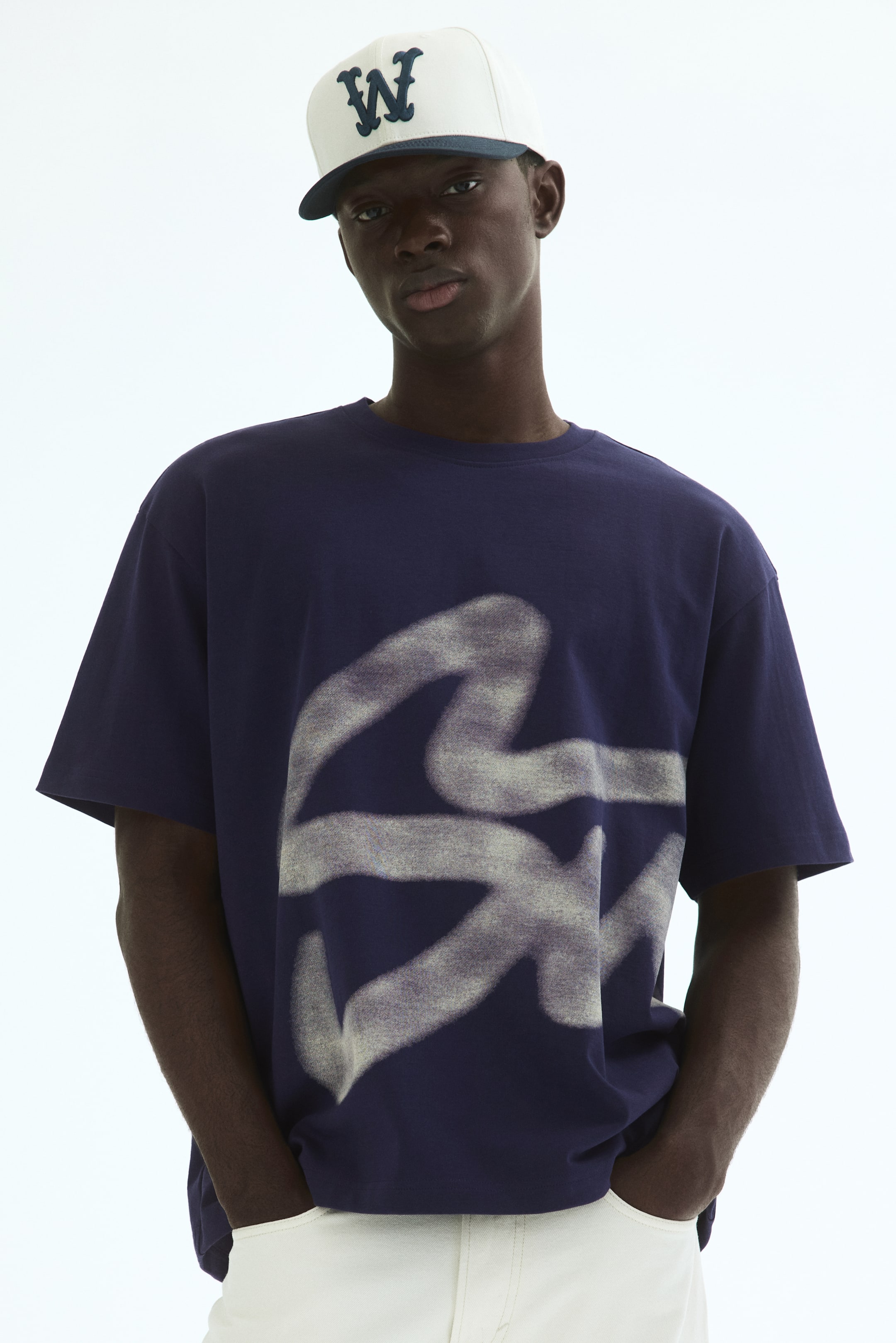 View larger image: A navy blue oversized t-shirt featuring a large, faded light grey abstract graphic across its front. It displays short sleeves and a crew neck.