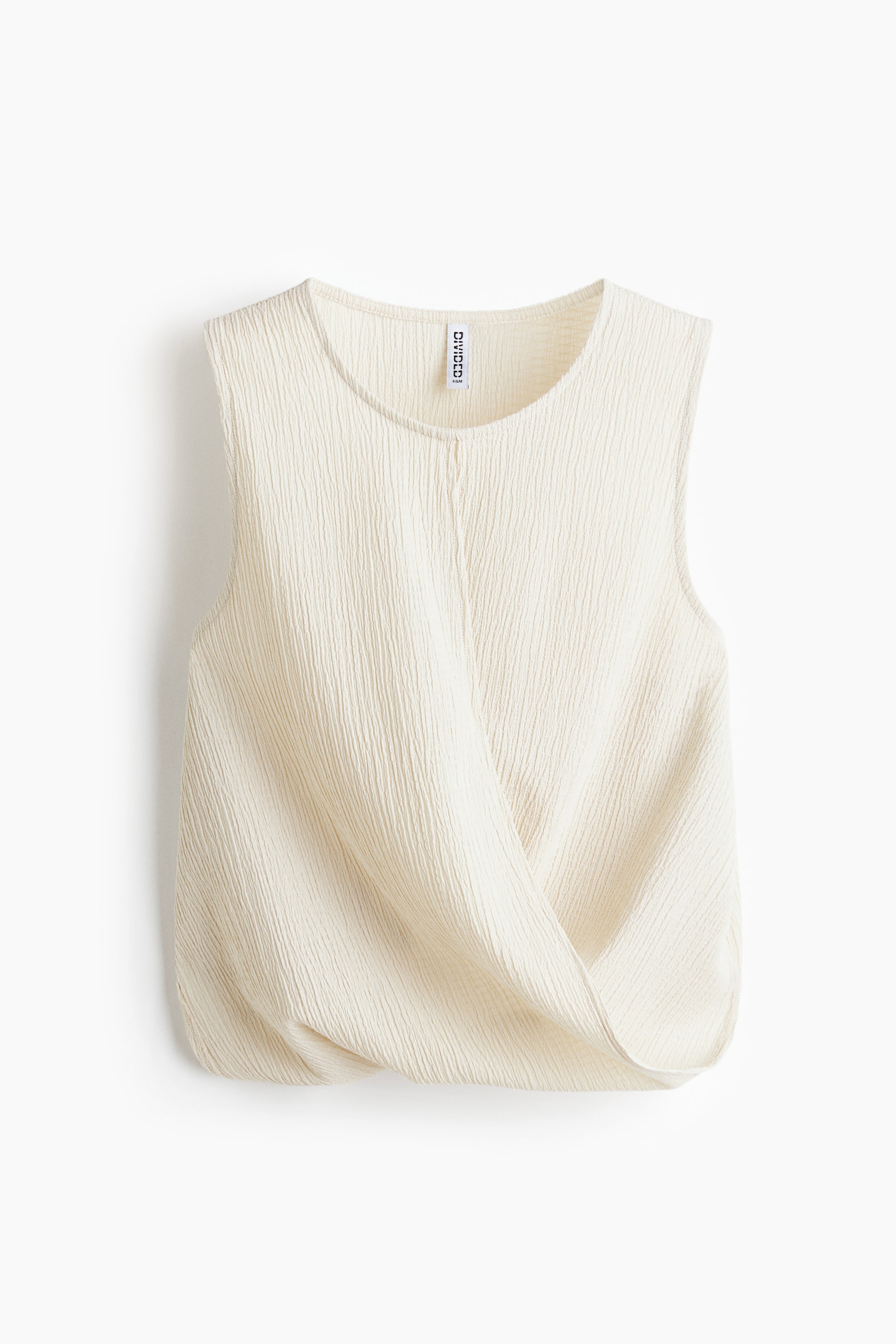 View larger image: A cream sleeveless top displays a crinkled texture and a round neckline. The front boasts a crossover wrap design, creating a draped effect, with a small white label visible on the inner back neckline.