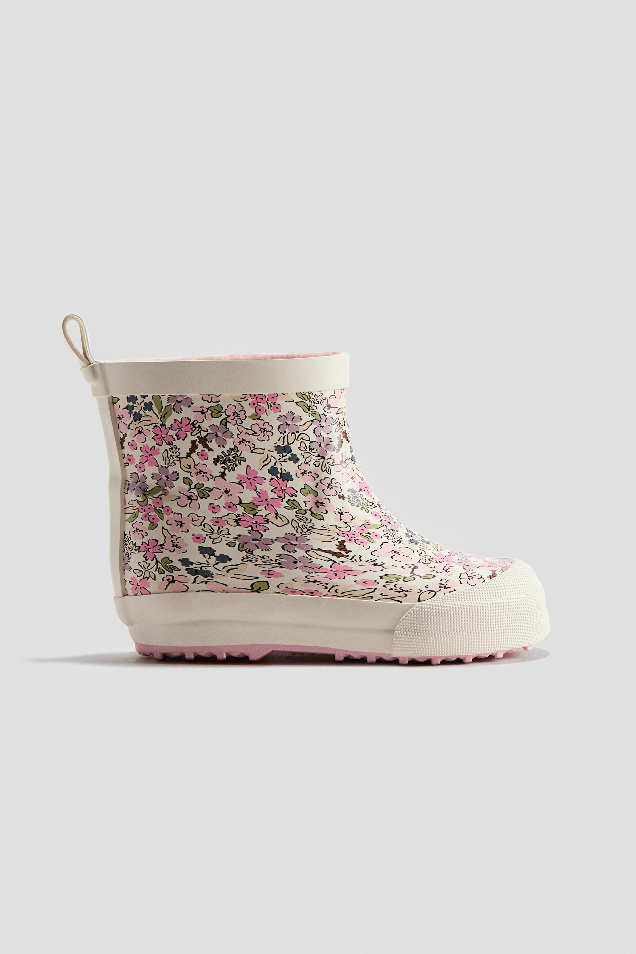 查看大圖: 這款 Wellington boot 採用奶油色底布，飾有粉紅、紫及綠色花朵。靴口頂端可見粉紅色襯裡；厚實的奶油色鞋底配有粉紅色圖案的防滑紋路，並延伸至具紋理的鞋頭護片。