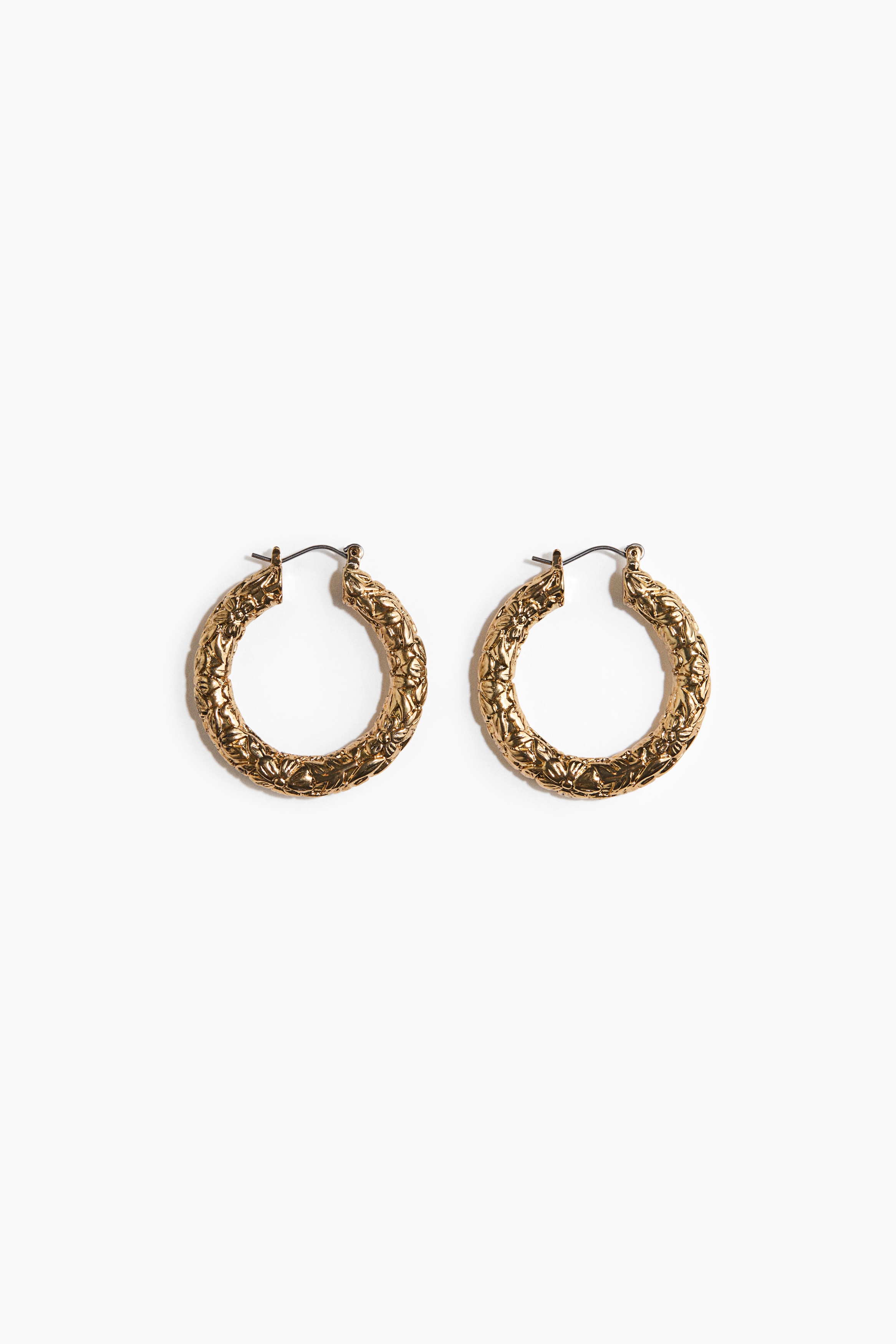 Des crÃ©oles texturÃ©es ton dorÃ© sont portÃ©es par le mannequin. Ces boucles dâoreilles Ã©paisses et texturÃ©es sâaccordent avec des lunettes de soleil Ã  monture sombre et un haut beige Ã  col montant.