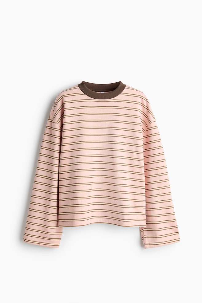 An oversized, long-sleeved sweatshirt featuring a pink and brown horizontal stripe pattern is shown from the front, highlighting its relaxed fit and dropped shoulders. It is designed with wide, straight-cut sleeves, a straight hem, and a contrasting dark brown ribbed crew neckline. - 1