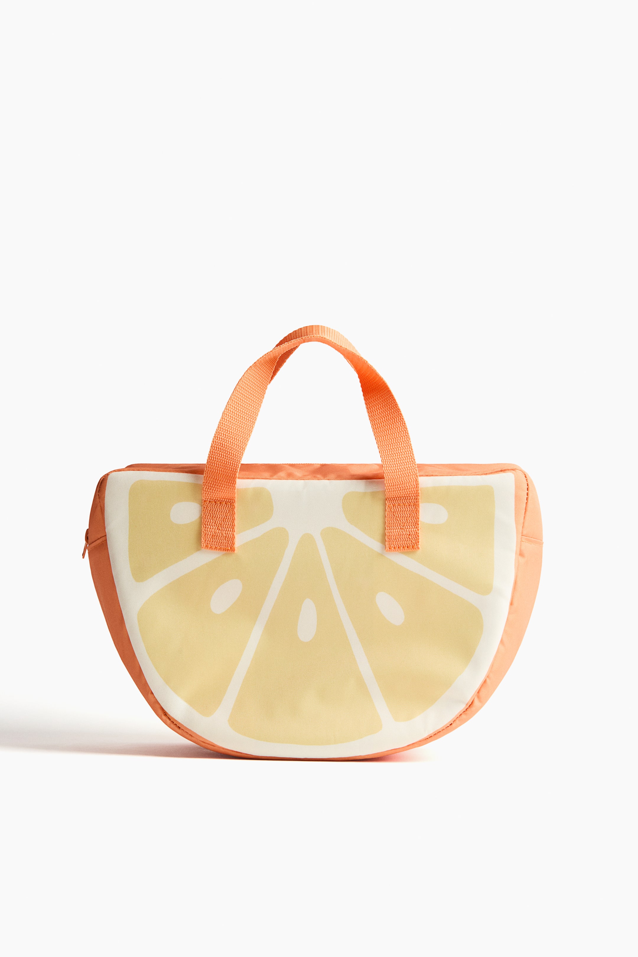Ampliar la imagen: Una lonchera vista de frente tiene forma de media rodaja de fruta cítrica; presenta un patrón segmentado en blanco y amarillo claro en su superficie principal, con costados sólidos de color naranja. Dos asas cortas de tela naranja están fijadas en la parte superior, y una cremallera recorre el borde curvo izquierdo.
