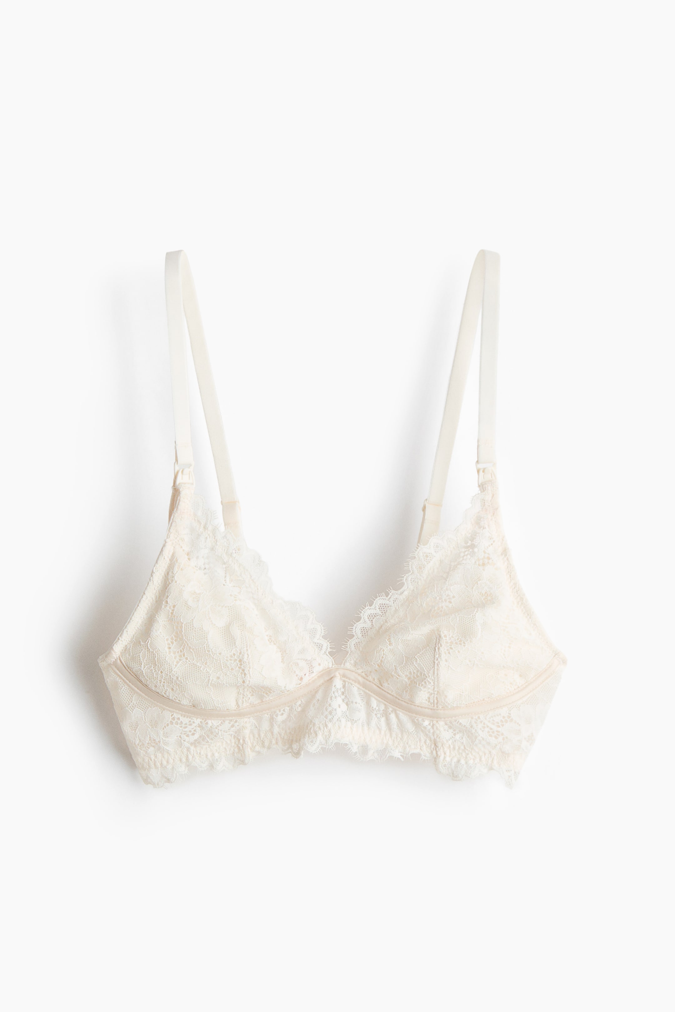 Visualizza immagine più grande: Un morbido reggiseno per allattamento, senza ferretto, mostra la parte anteriore, realizzato in pizzo floreale color crema chiaro. Presenta coppe triangolari foderate con rifinitura in pizzo smerlata e spalline regolabili che si estendono verso l'alto.