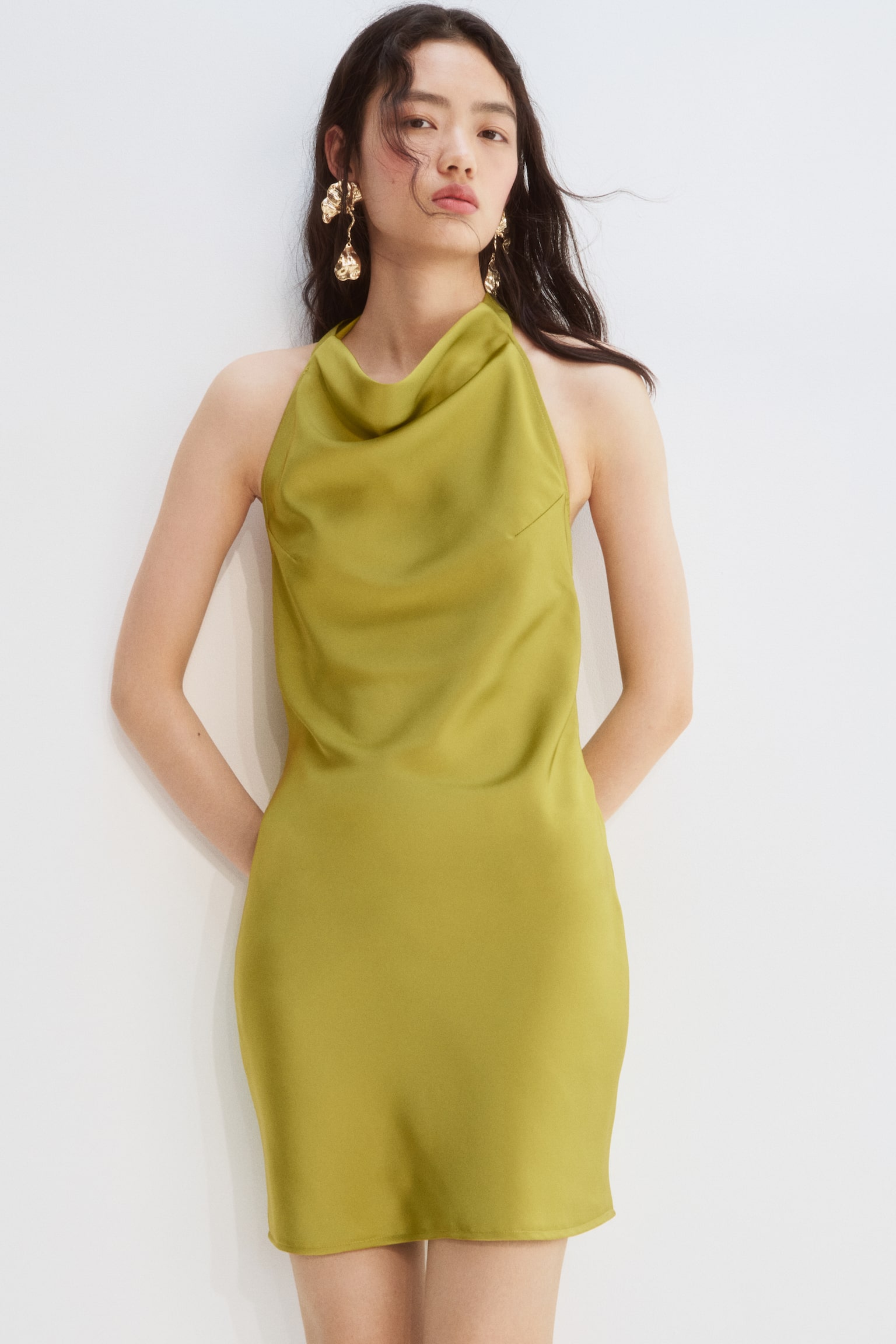 A chartreuse satin mini dress is being showcased, featuring a halter neckline with a soft cowl drape and a straight hemline falling above the knee. - 1
