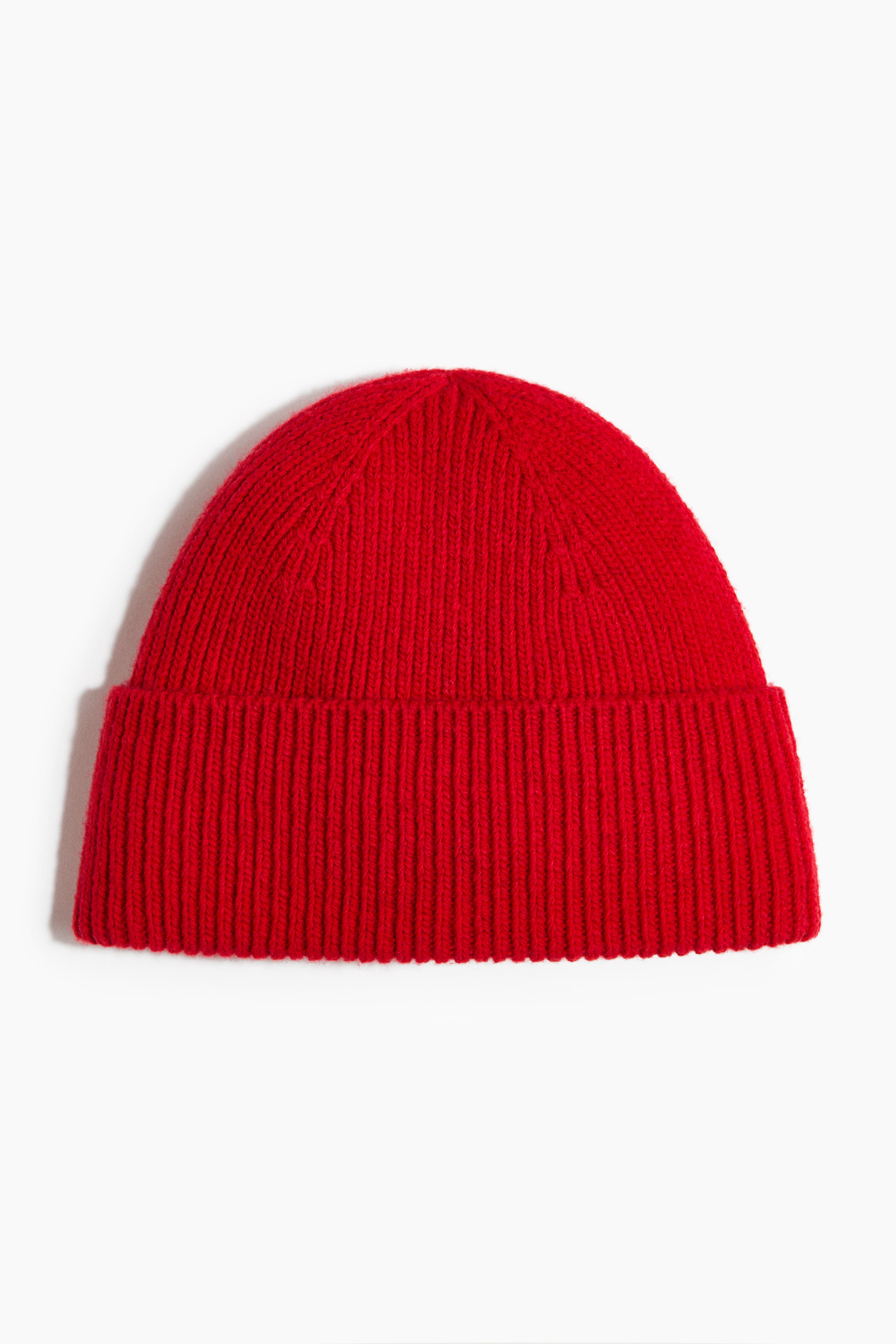 Grösseres Bild ansehen: Eine rote Strickmütze ist von vorne zu sehen und zeichnet sich durch einen breiten, gerippten Umschlagrand aus. Die Krone zeigt sichtbare Strickmaschen.