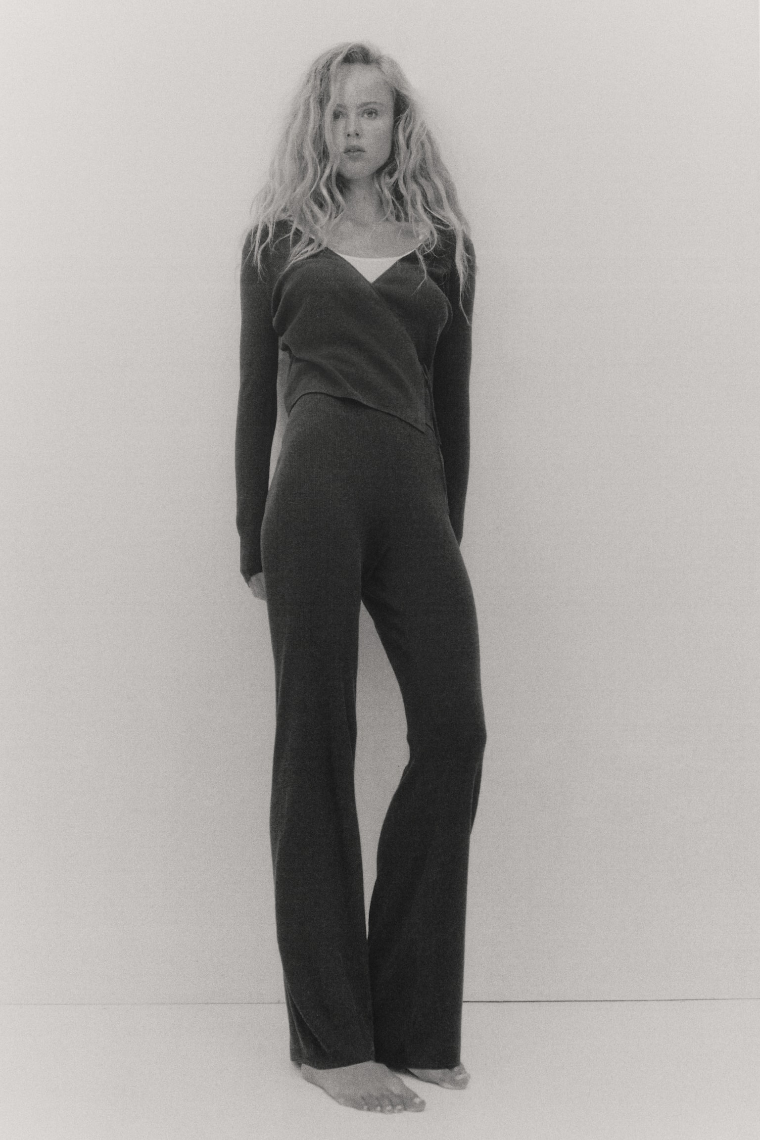 Black fitted trousers are shown flat, front-facing. They feature a distinct rib-knit texture, a smooth waistband, and straight legs. - 1
